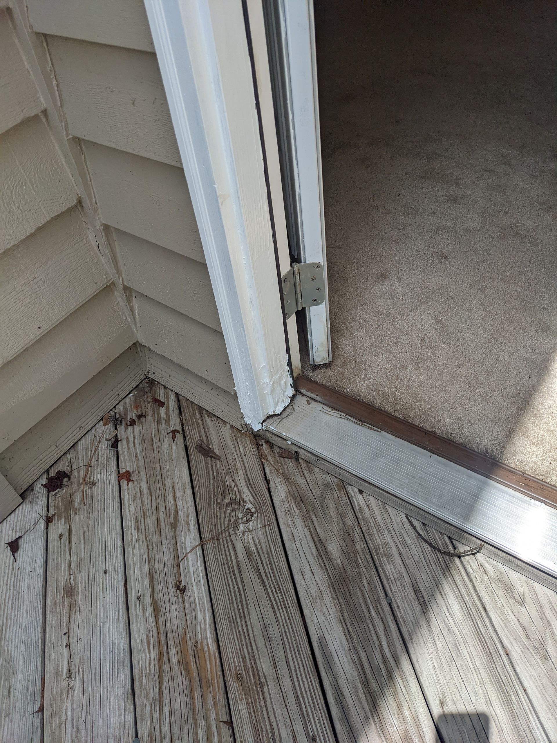 A close up of a door on a wooden deck next to a house.