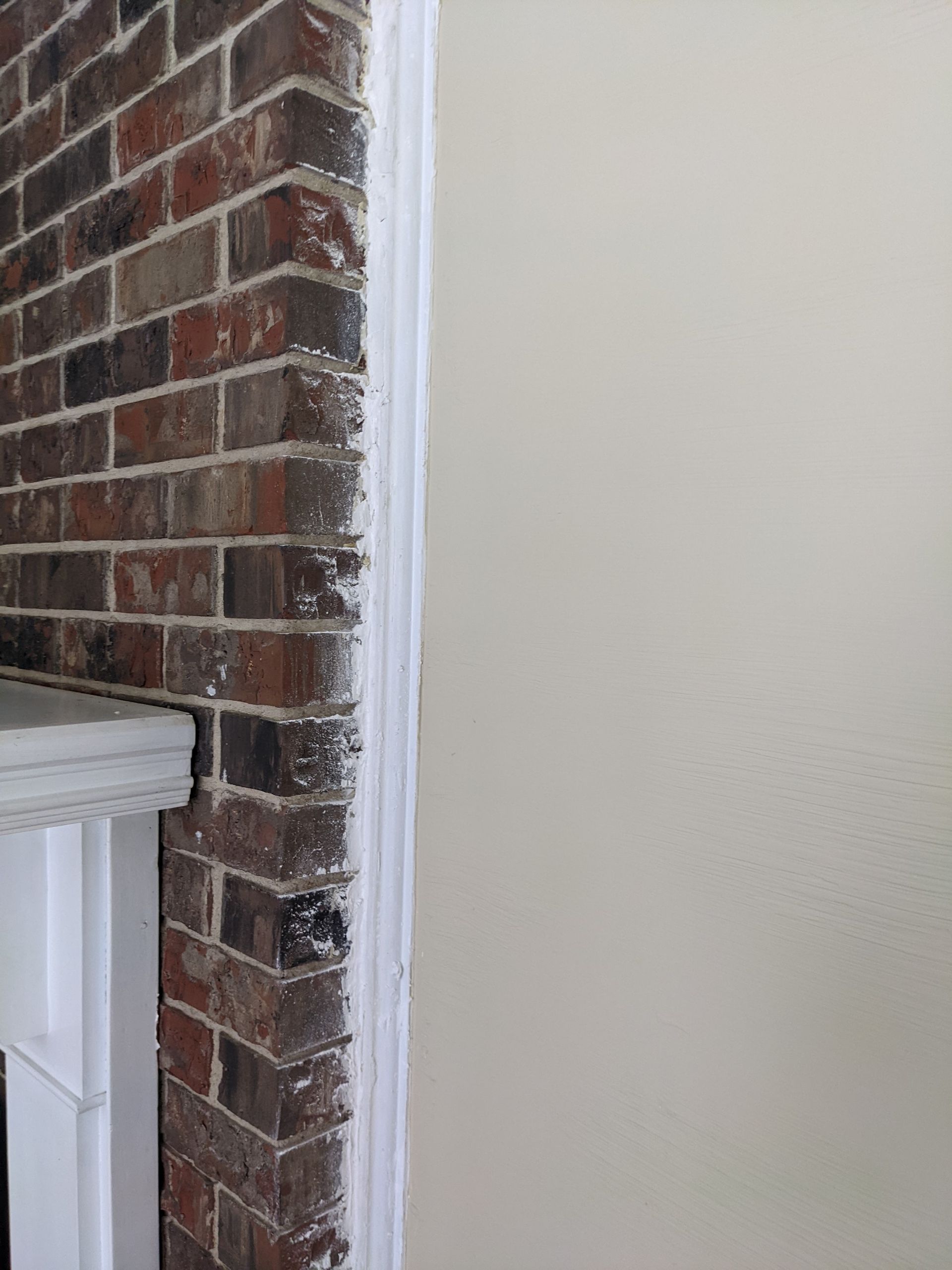A brick wall with a white trim and a fireplace in the background.