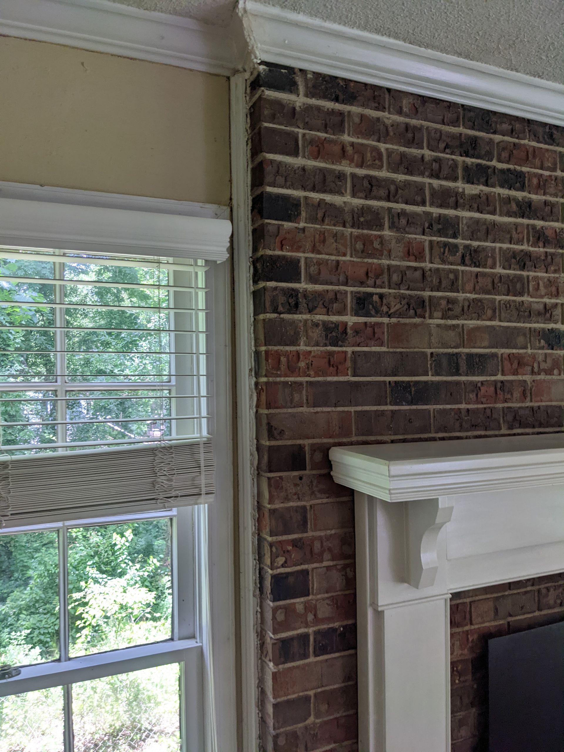 A living room with a fireplace , window and brick wall.