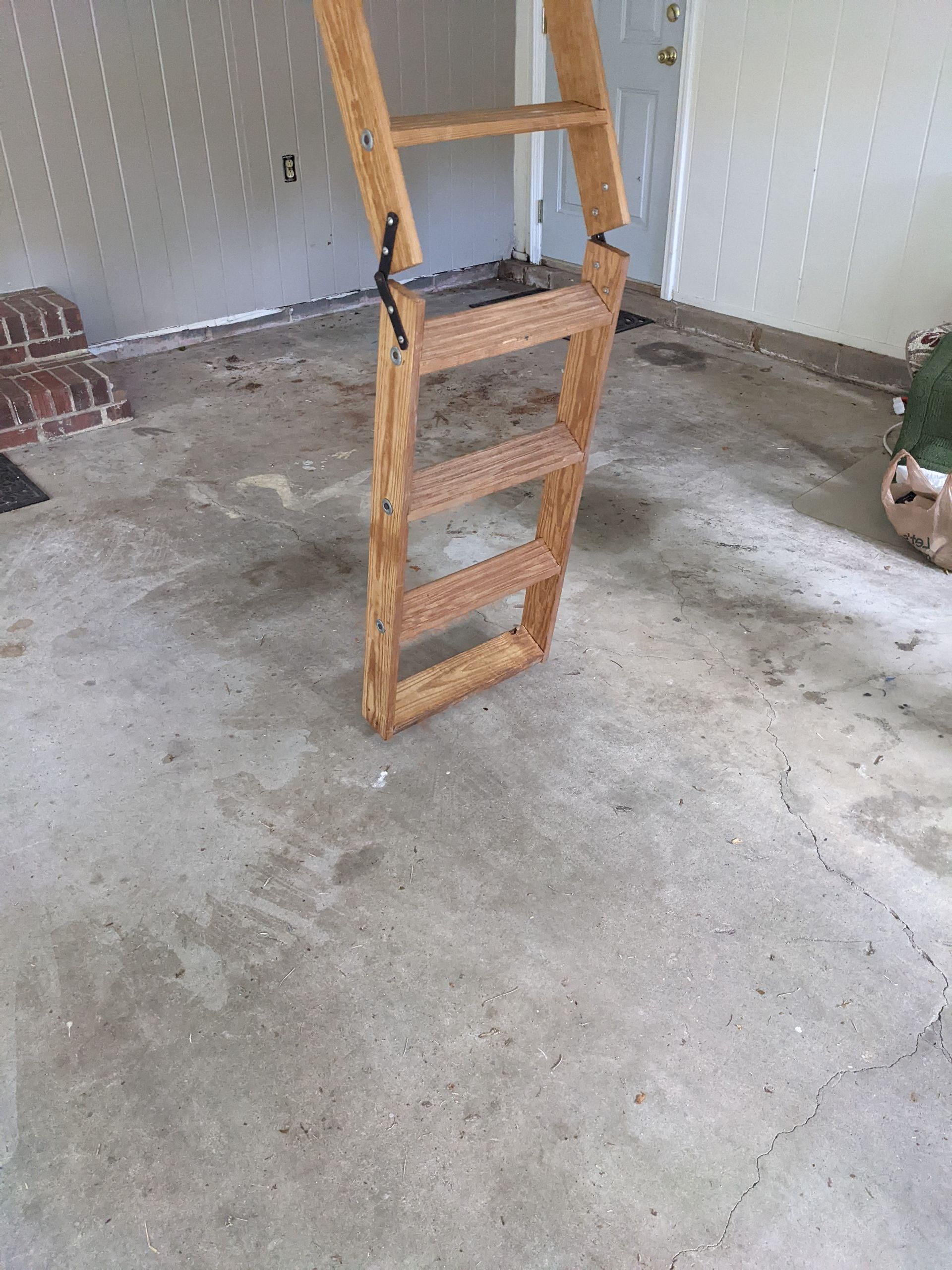 A wooden ladder is sitting on a concrete floor in a garage.