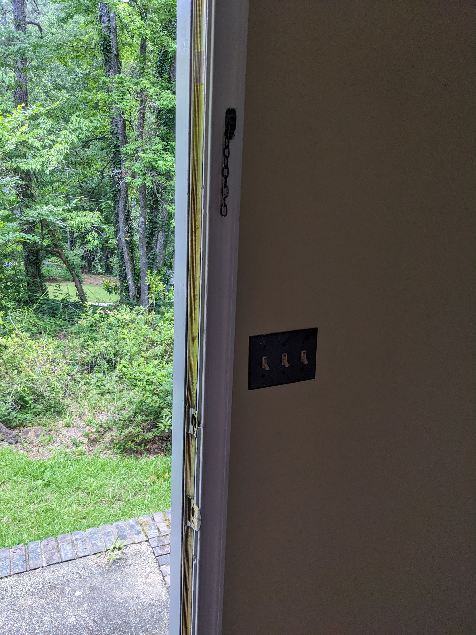 A door is open to a yard with trees in the background.