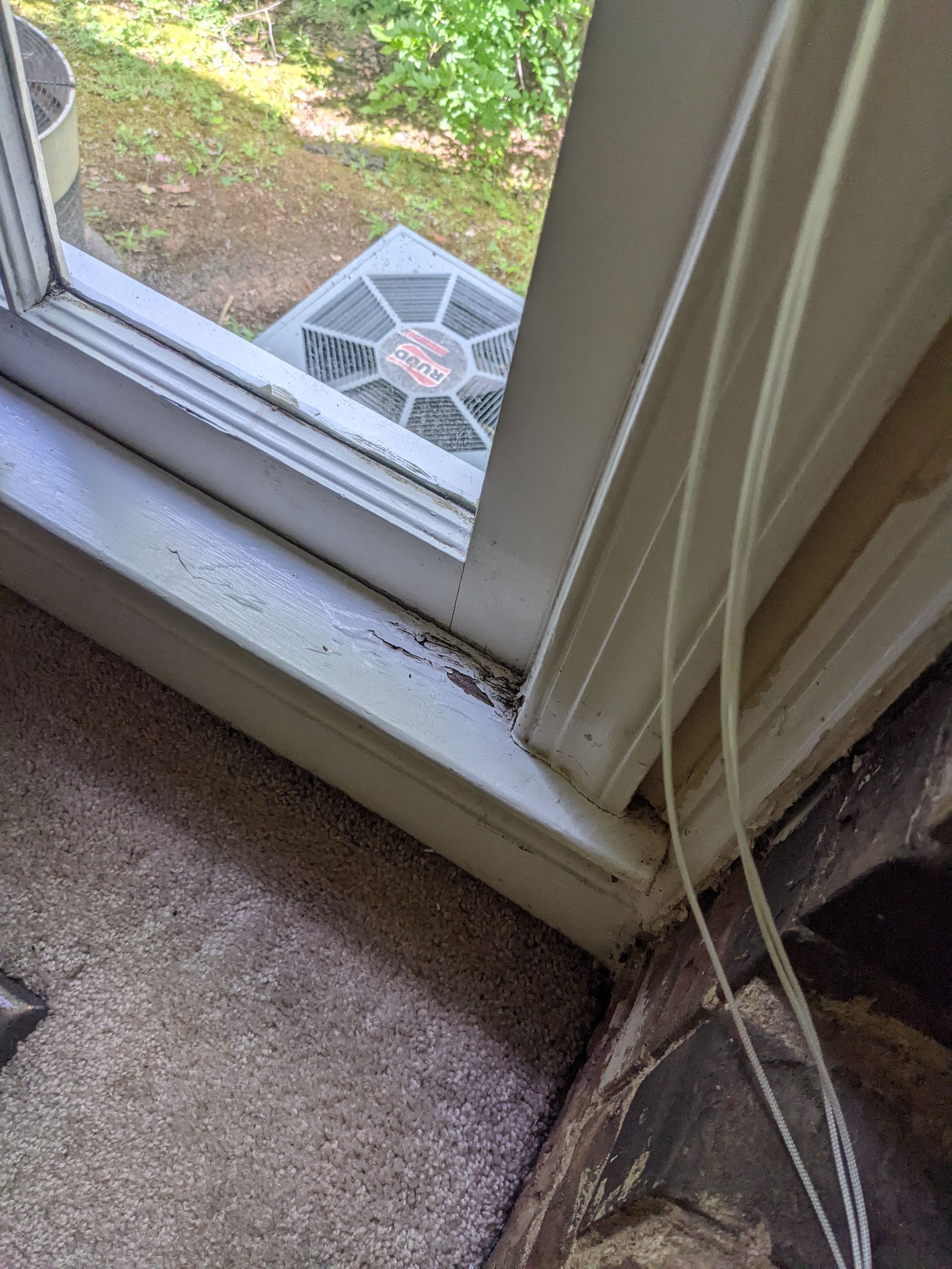 A close up of a window with a fan in the background.