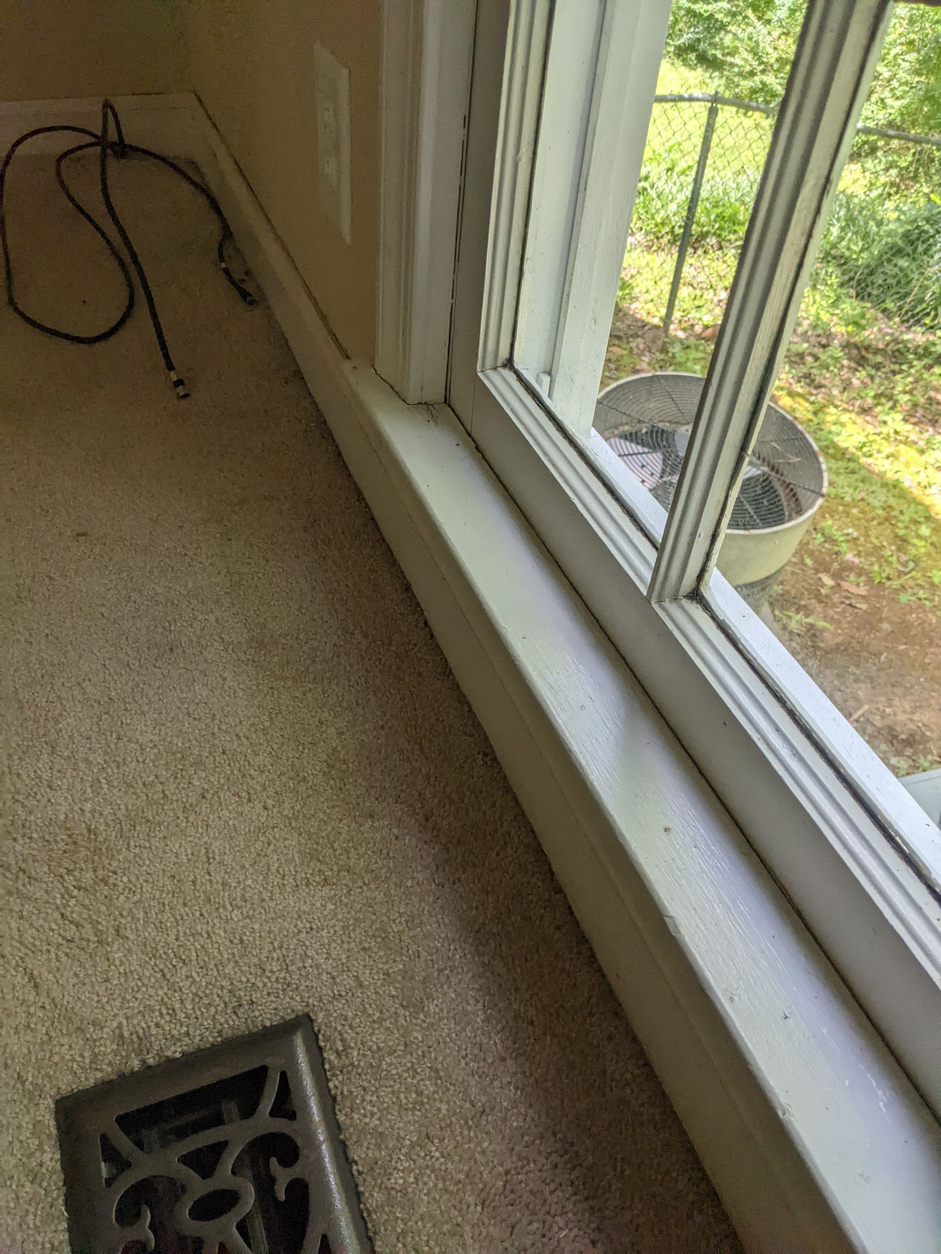 A room with a window and a vent on the floor.