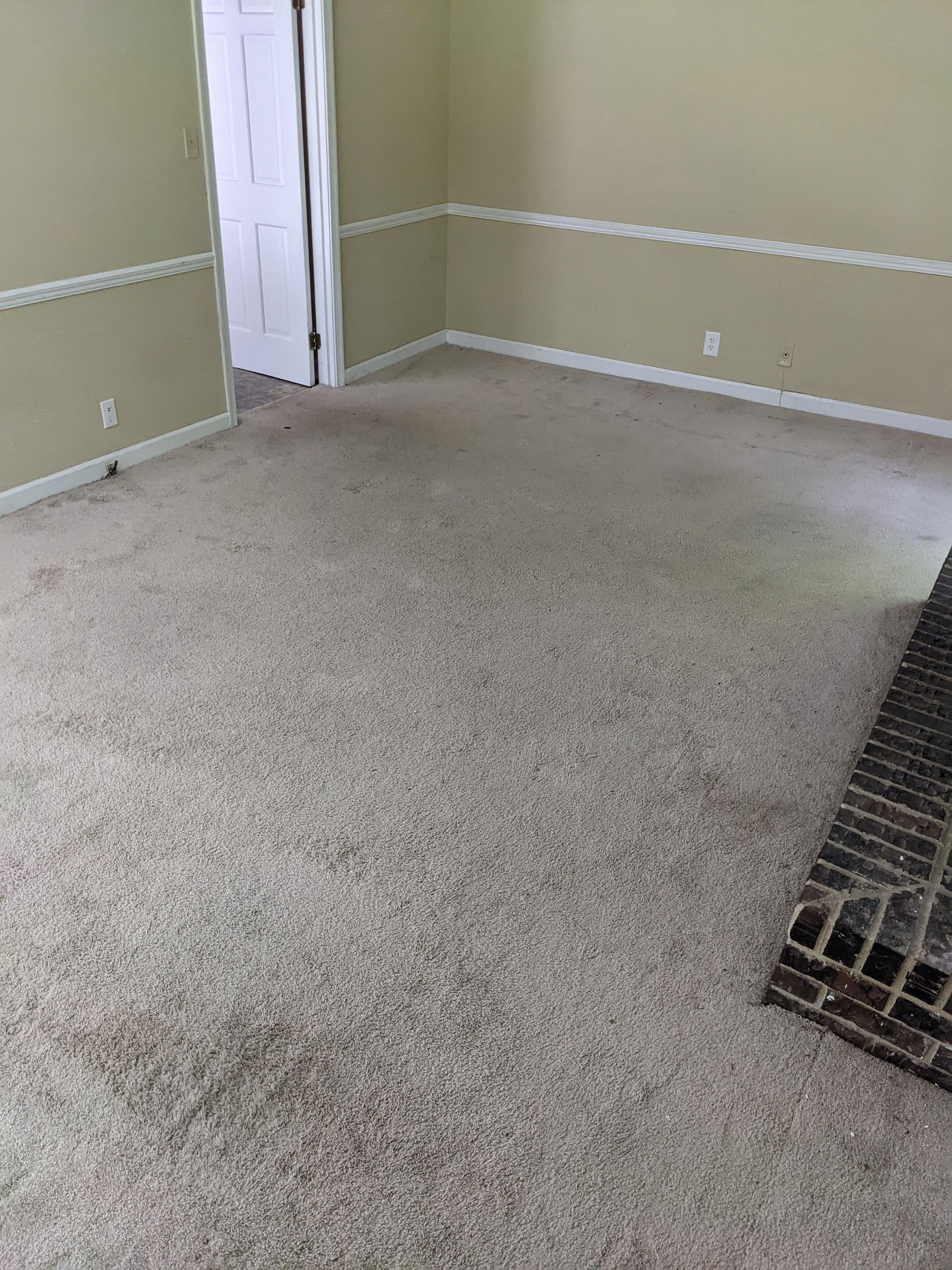 A living room with a fireplace and a carpeted floor.