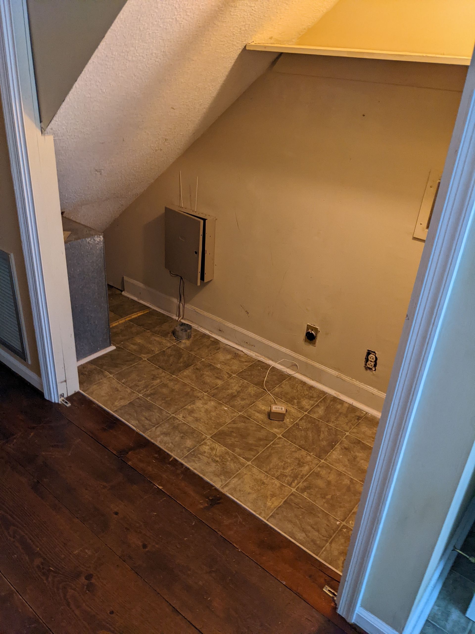 A closet under a staircase with a tile floor.
