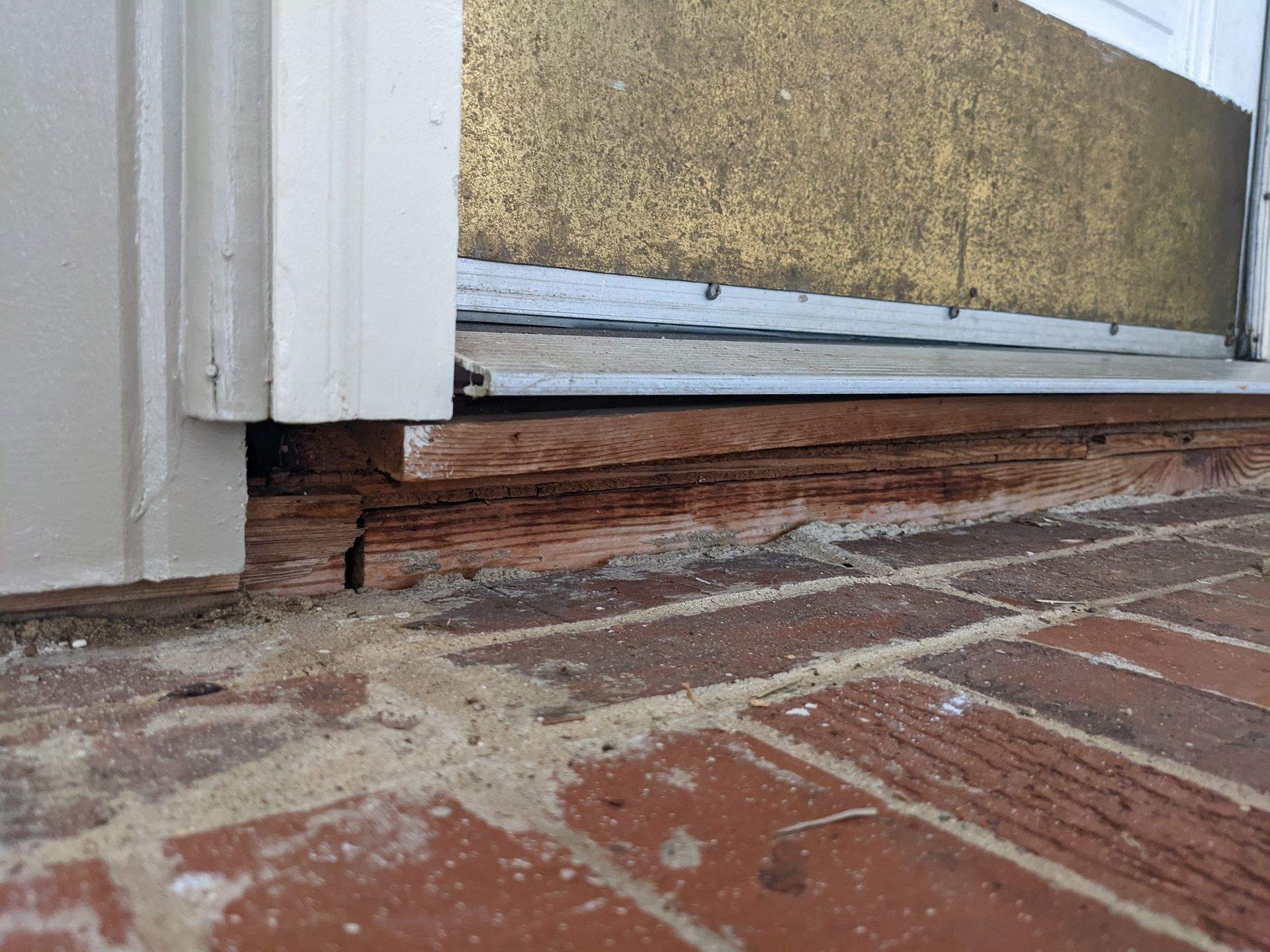 A brick floor next to a door with a wooden frame.