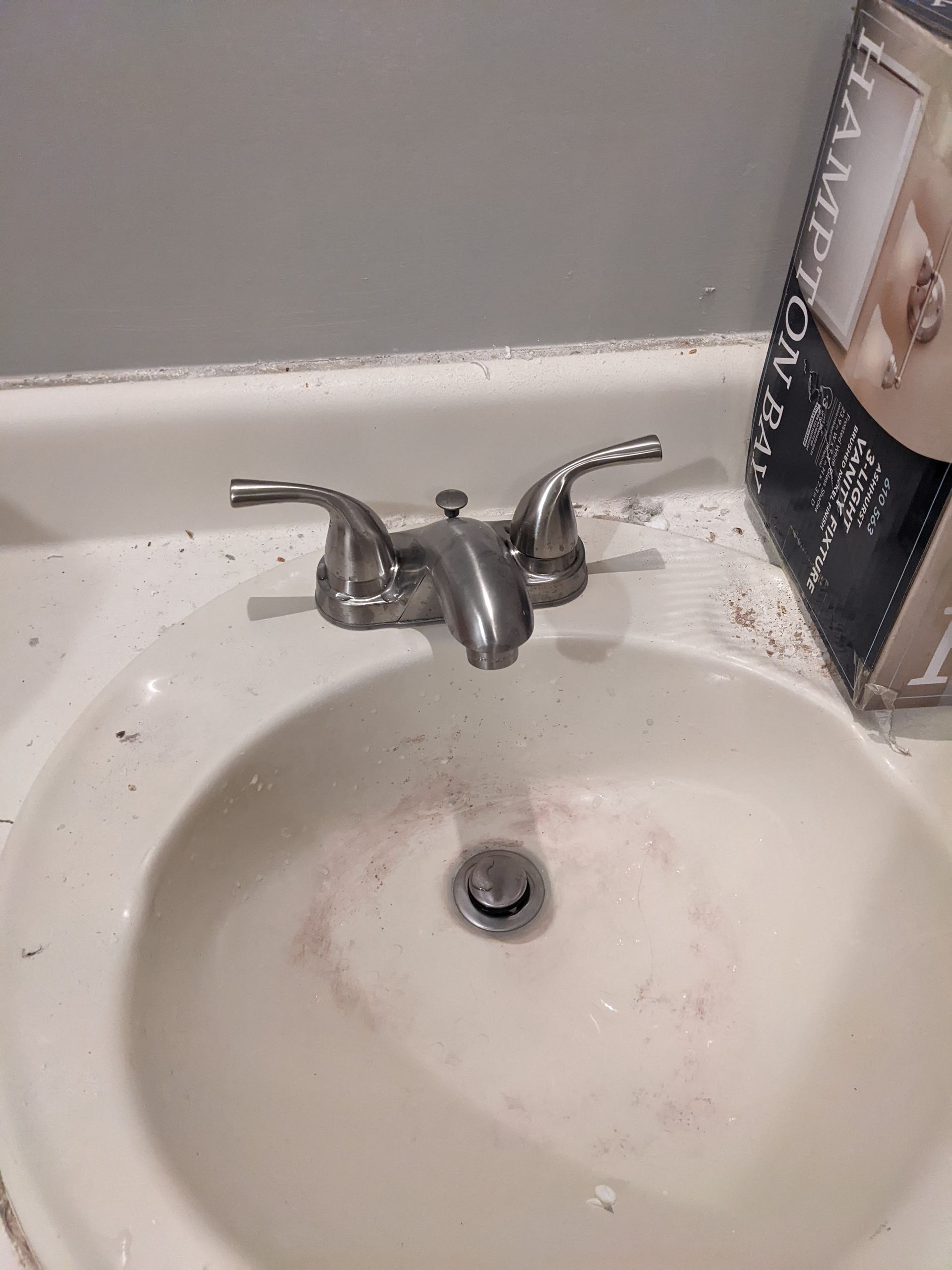 A bathroom sink with a faucet and a box next to it.