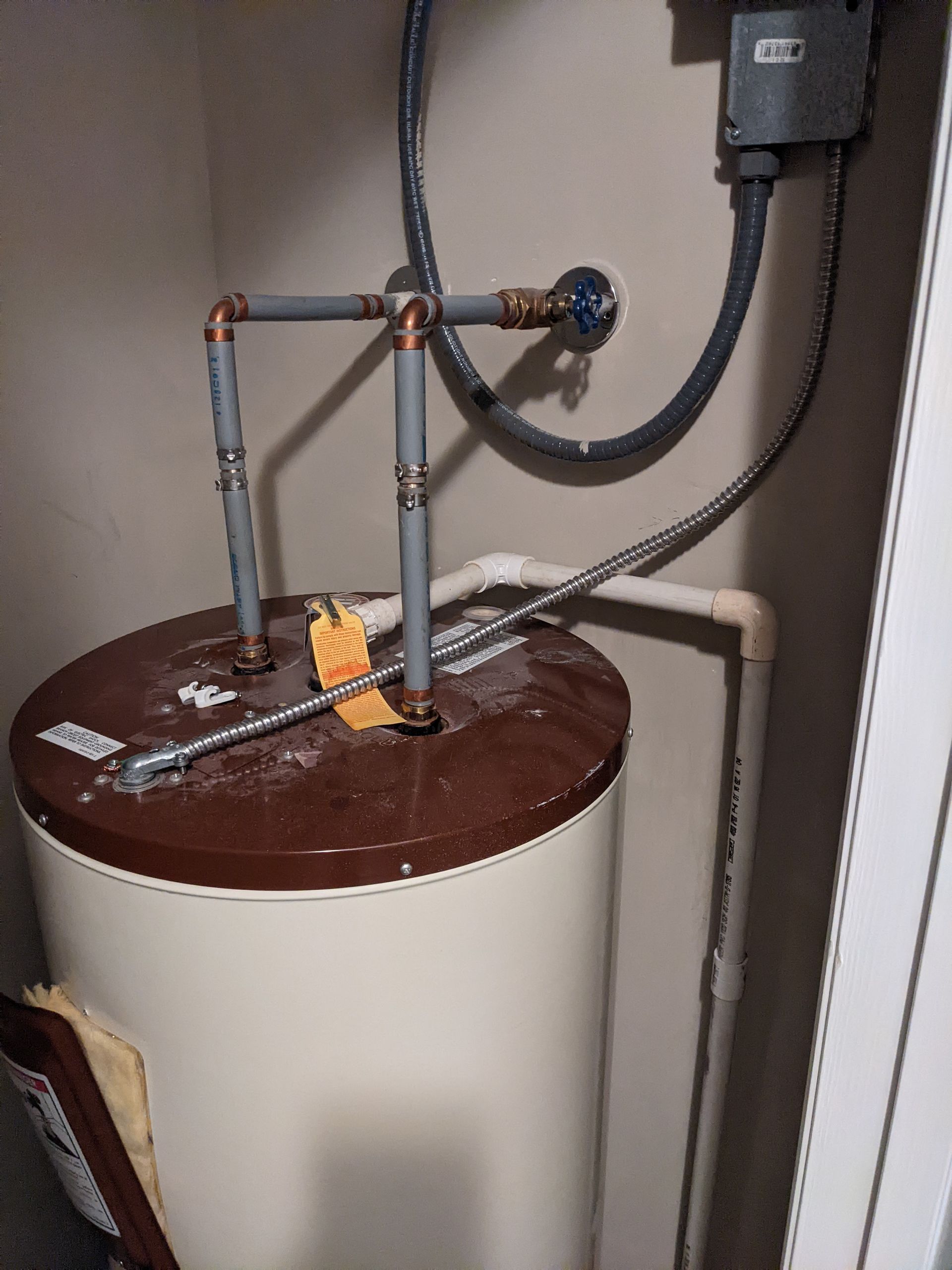 A brown and white water heater is sitting in a corner of a room.