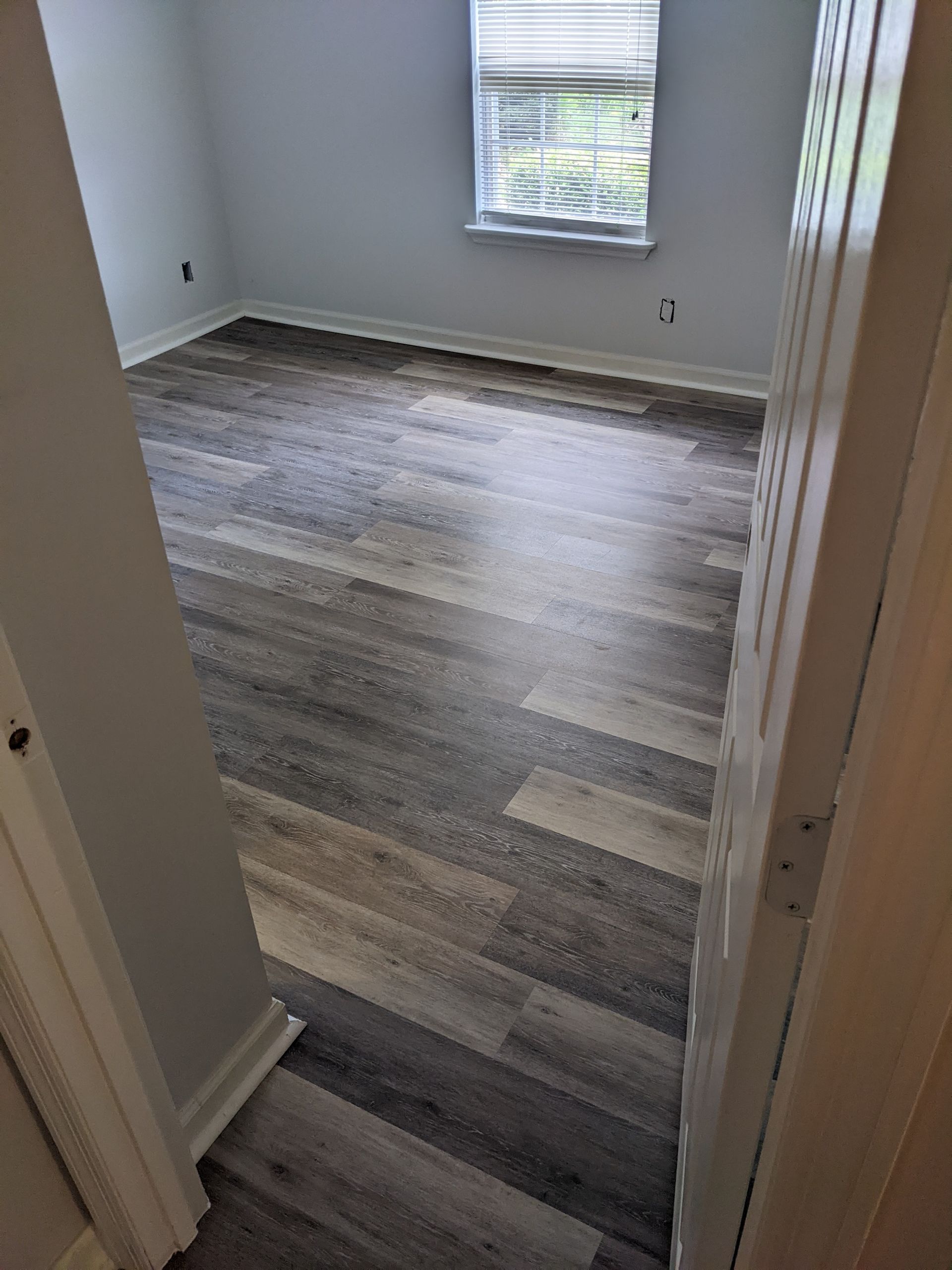 A bedroom with hardwood floors and a window.