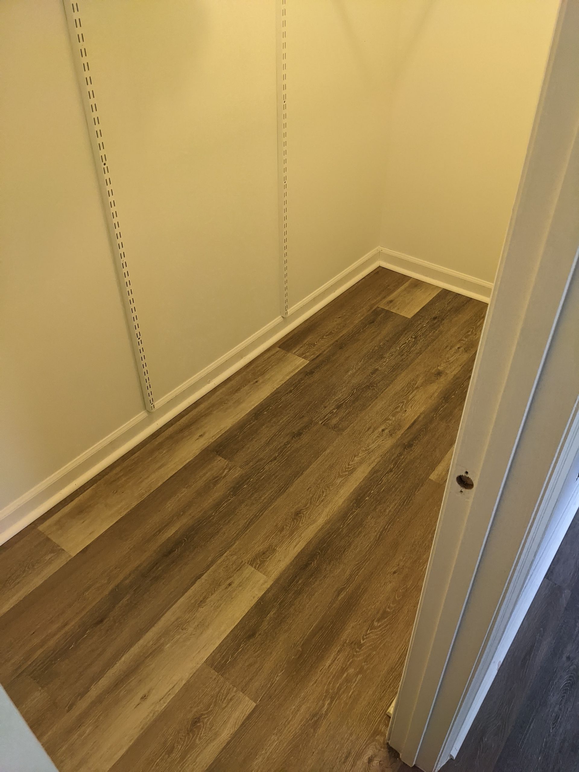 A small closet with hardwood floors and white walls.