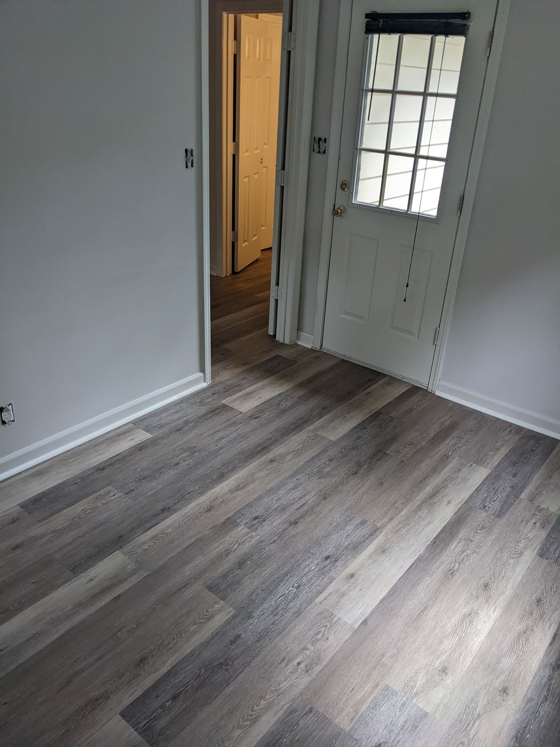 A room with hardwood floors , a door and a window.