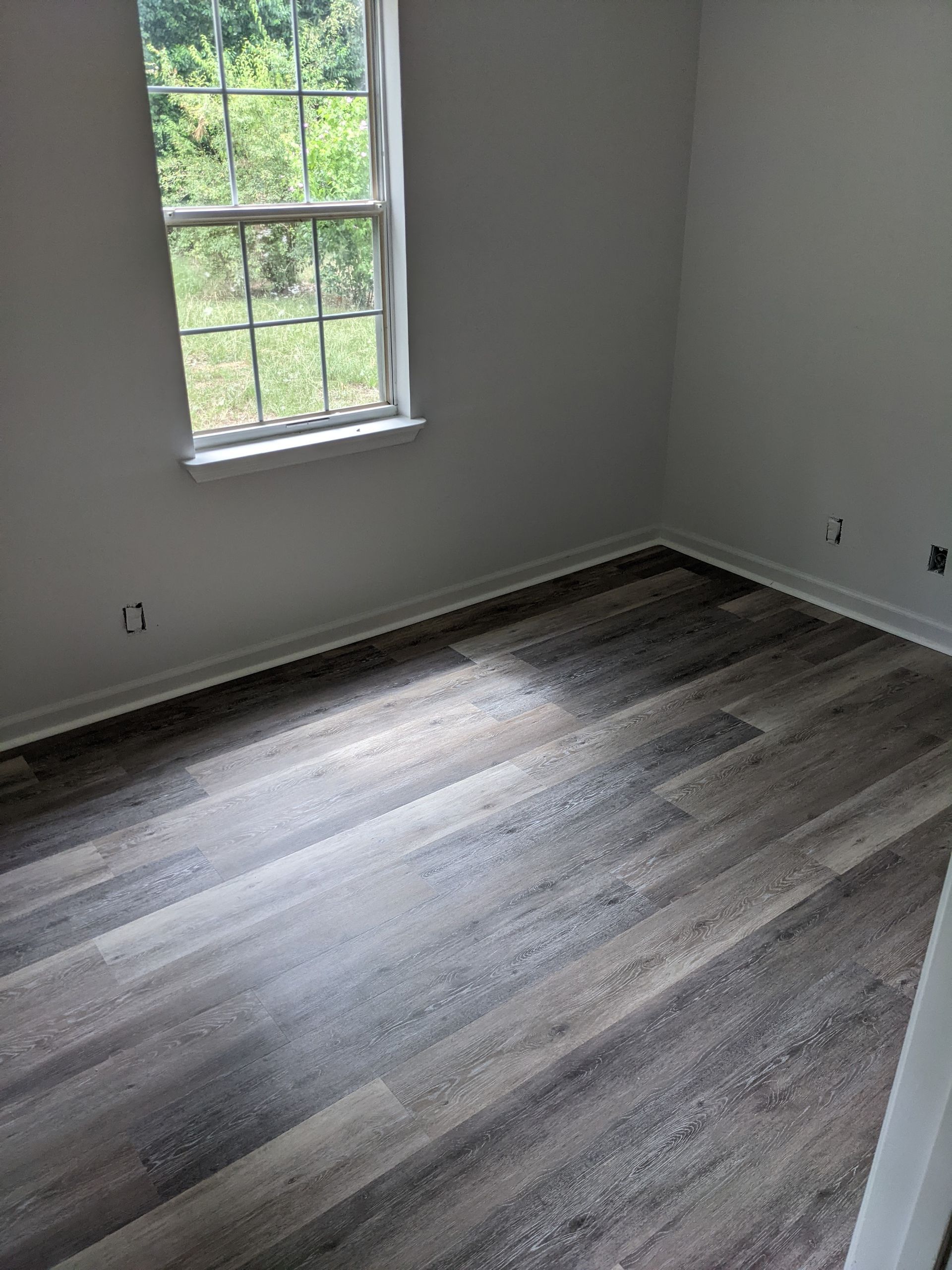 A bedroom with hardwood floors and a window.
