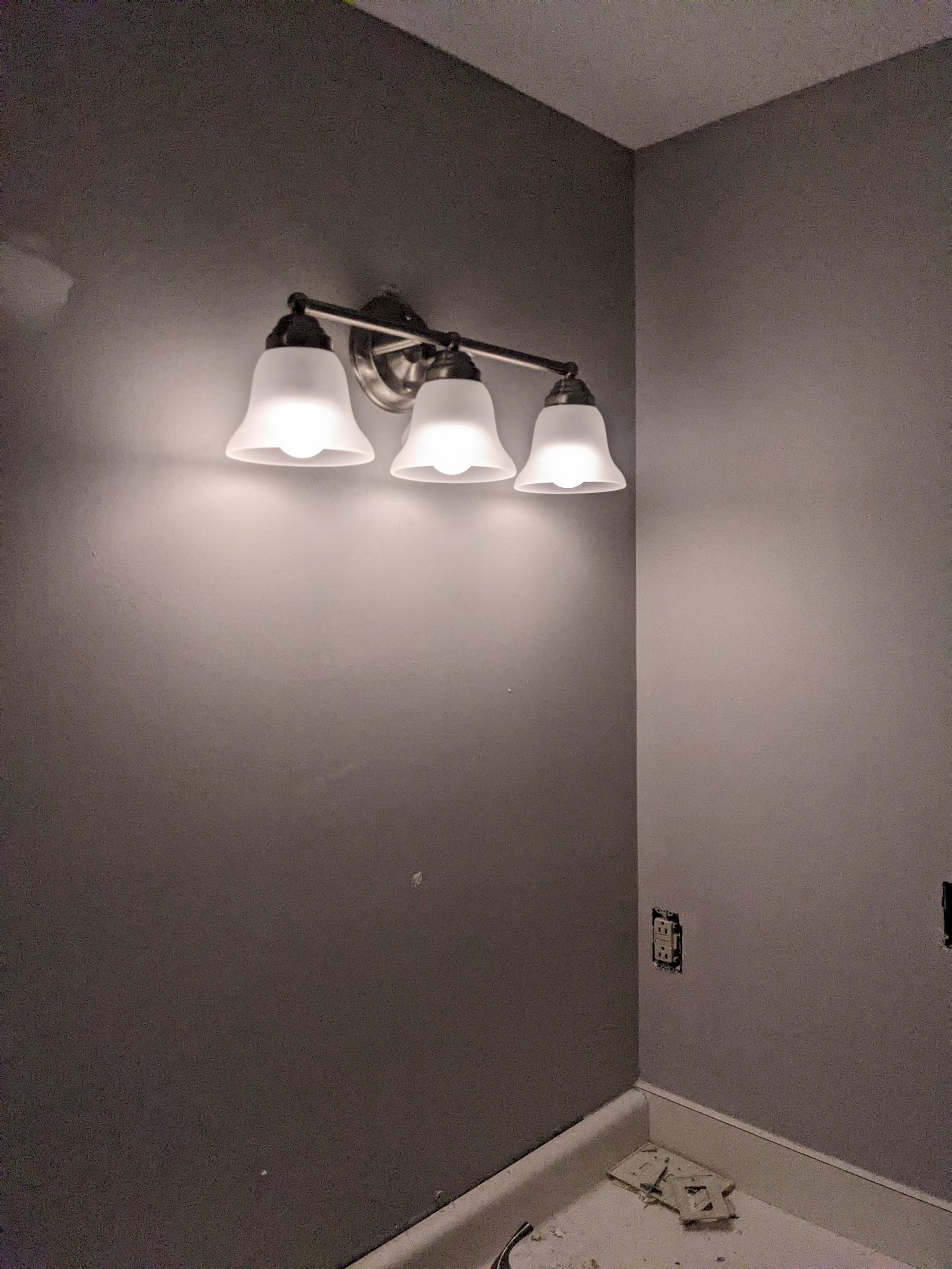 A bathroom vanity light is hanging on a wall in a bathroom.