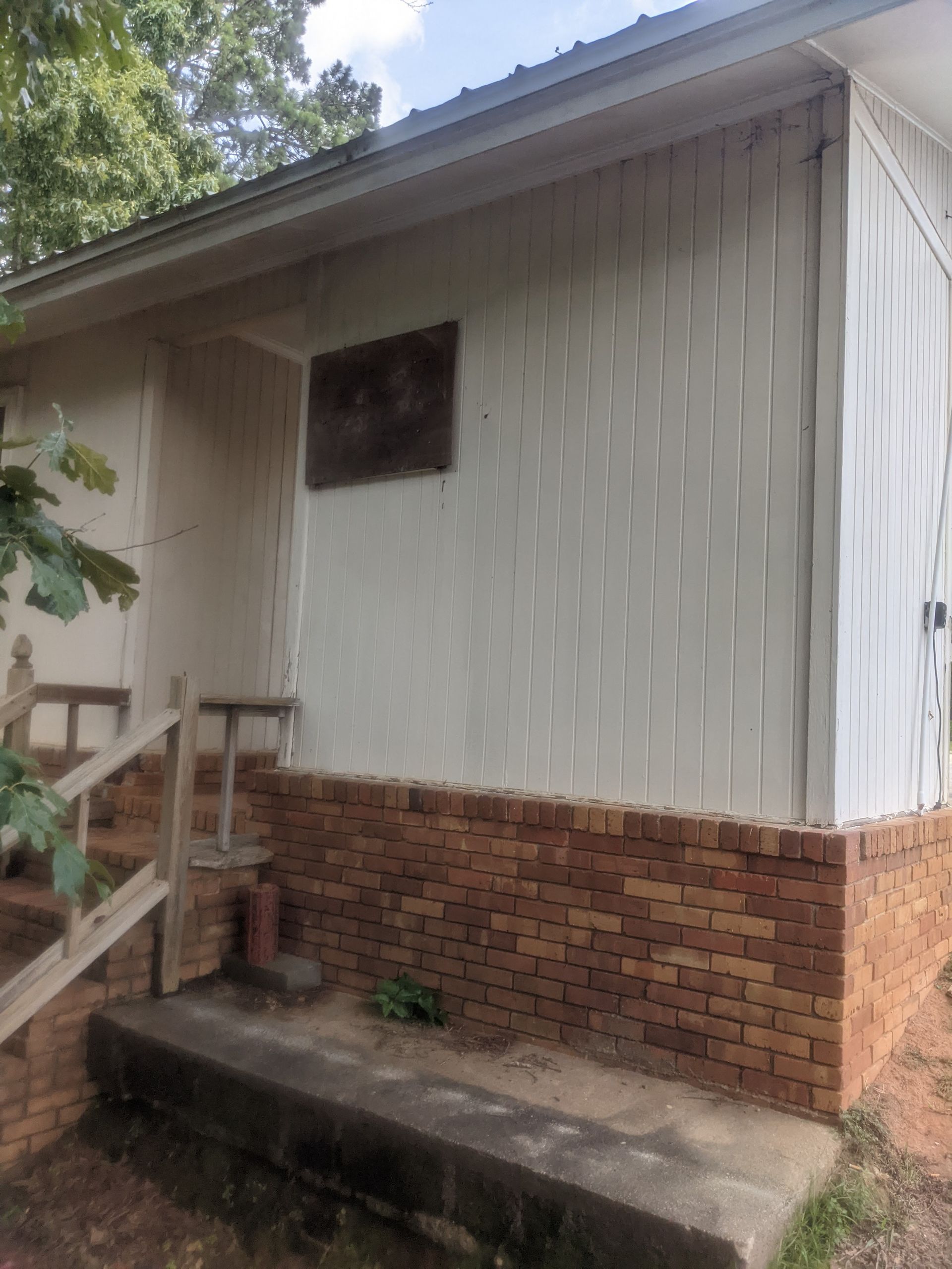 A small white house with a brick porch and stairs.