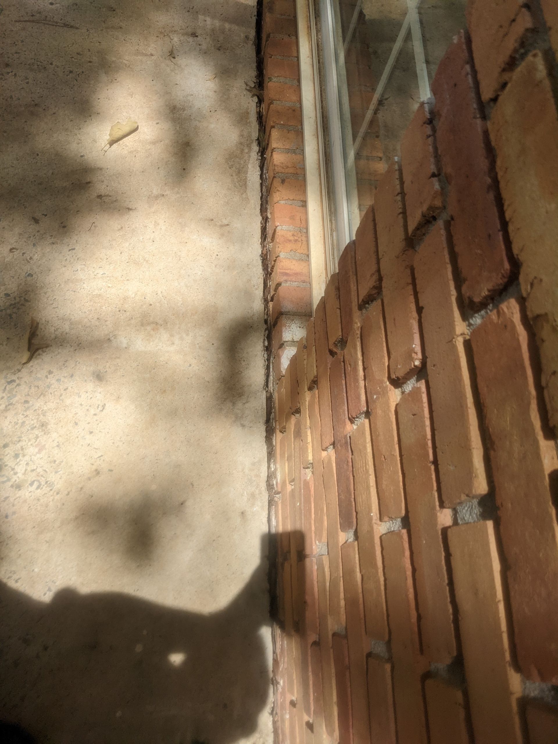 A shadow of a person is cast on a brick wall next to a window.