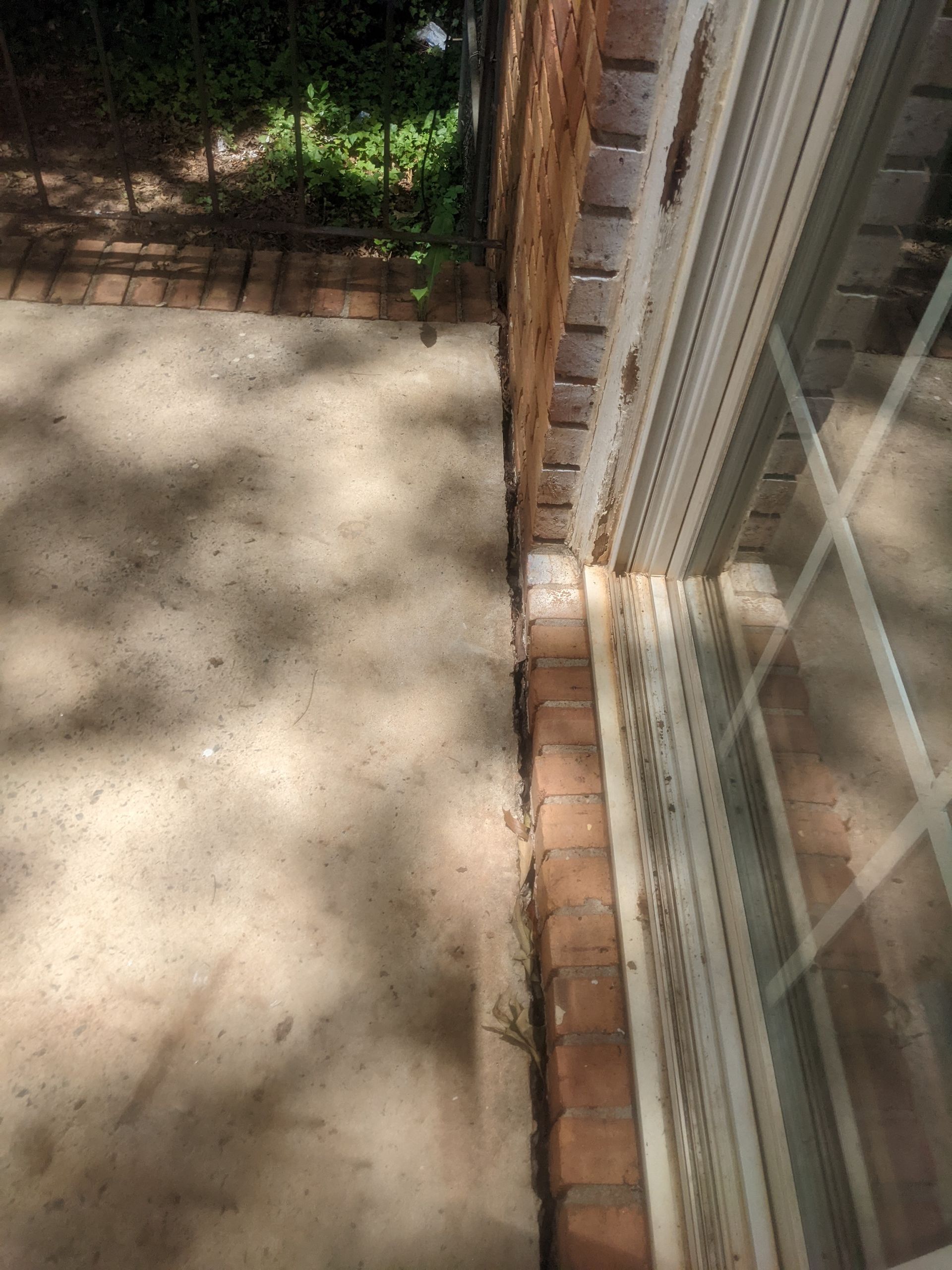 A sliding glass door is sitting on a concrete patio next to a brick wall.