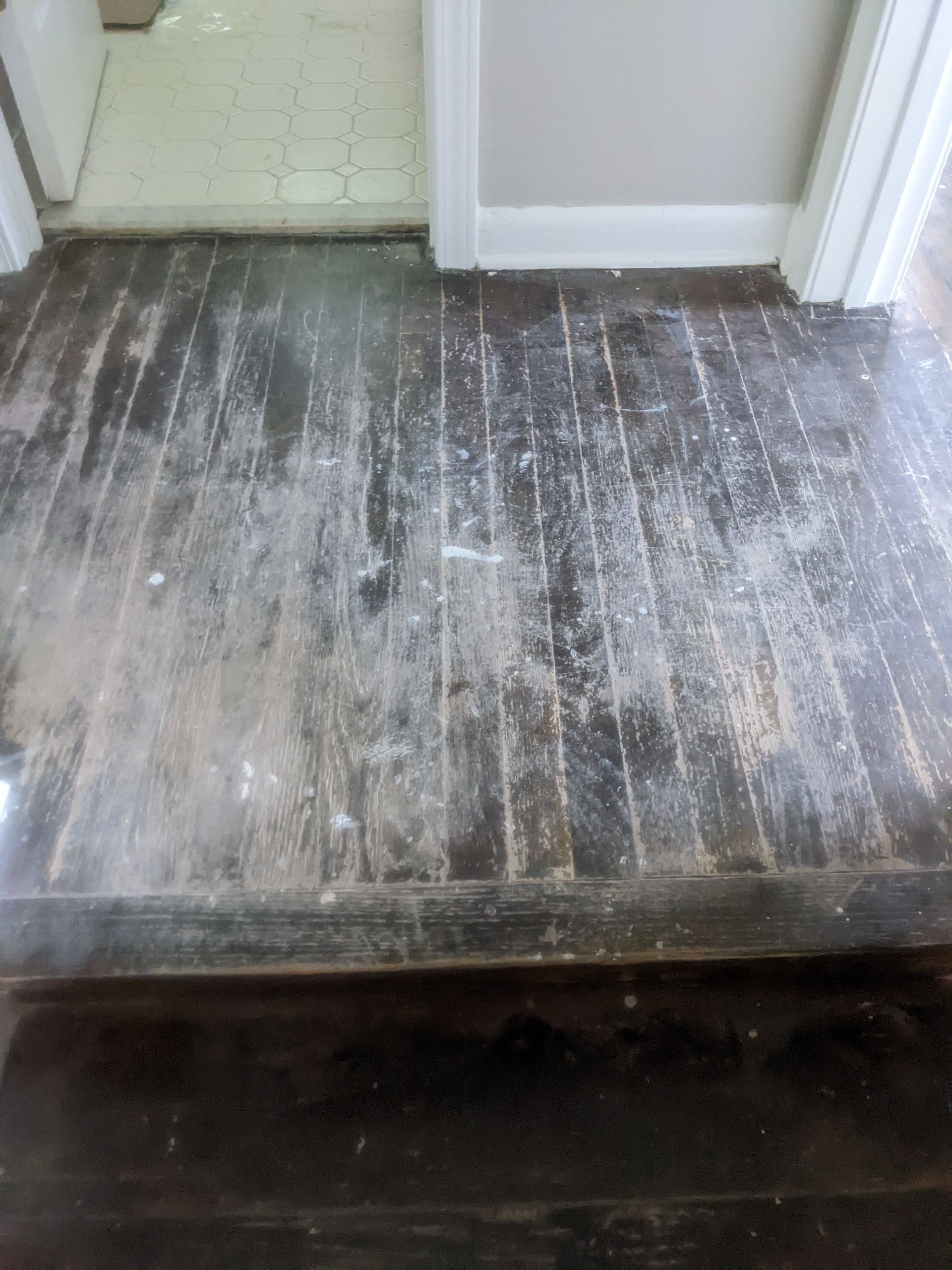 A wooden floor in a room next to a door.