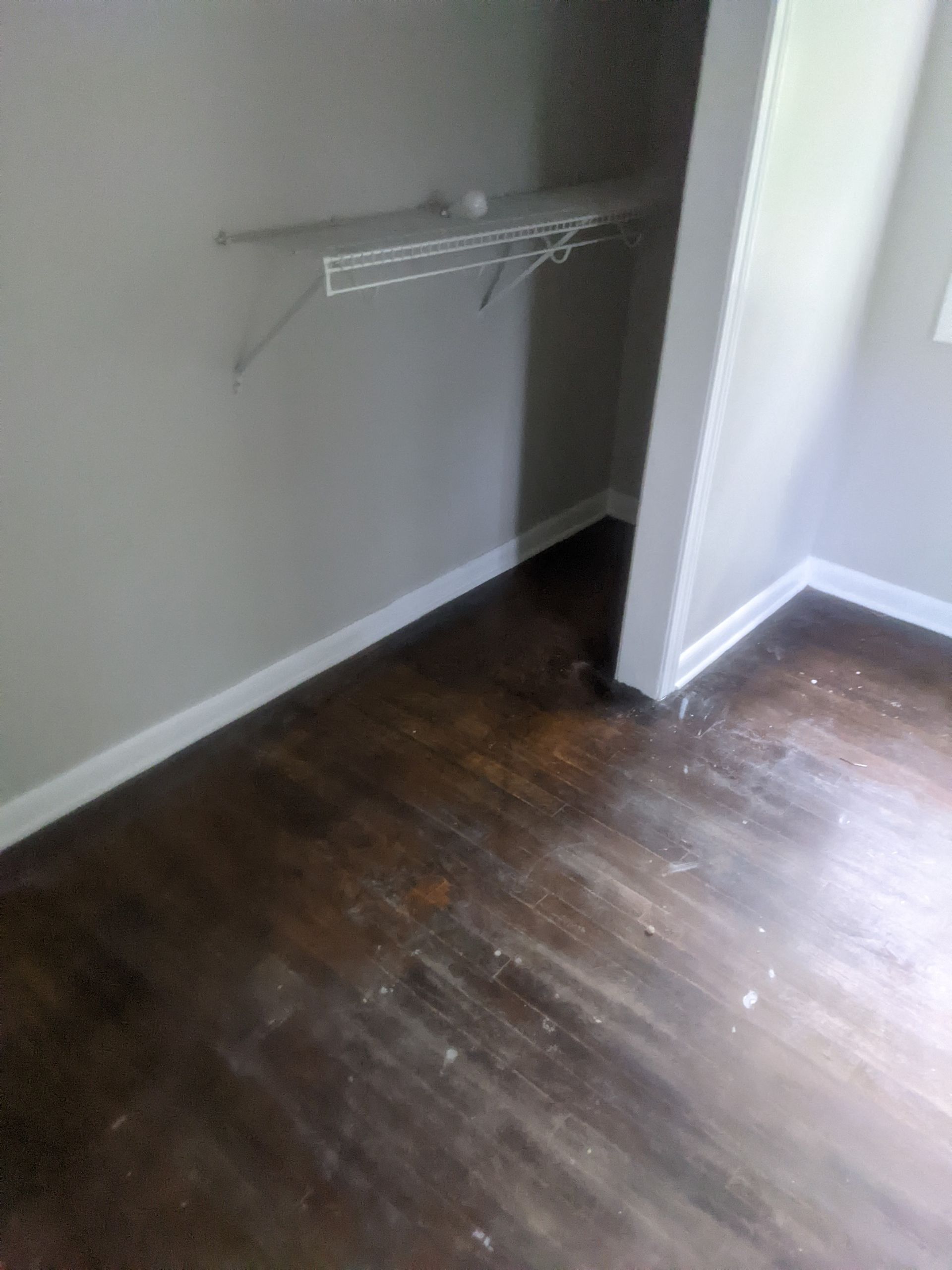 A room with a wooden floor and a shelf on the wall.