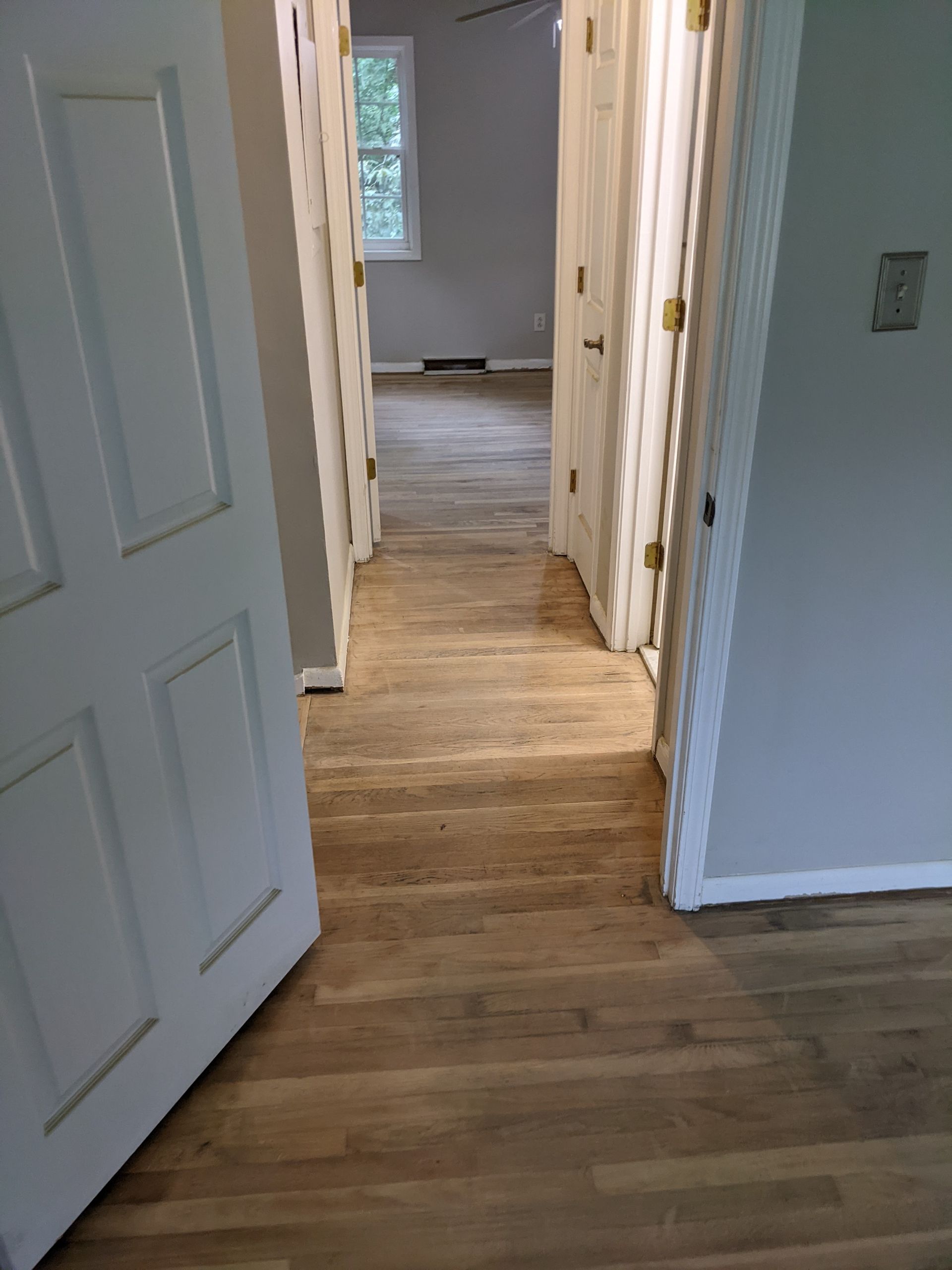 A hallway with hardwood floors and white doors