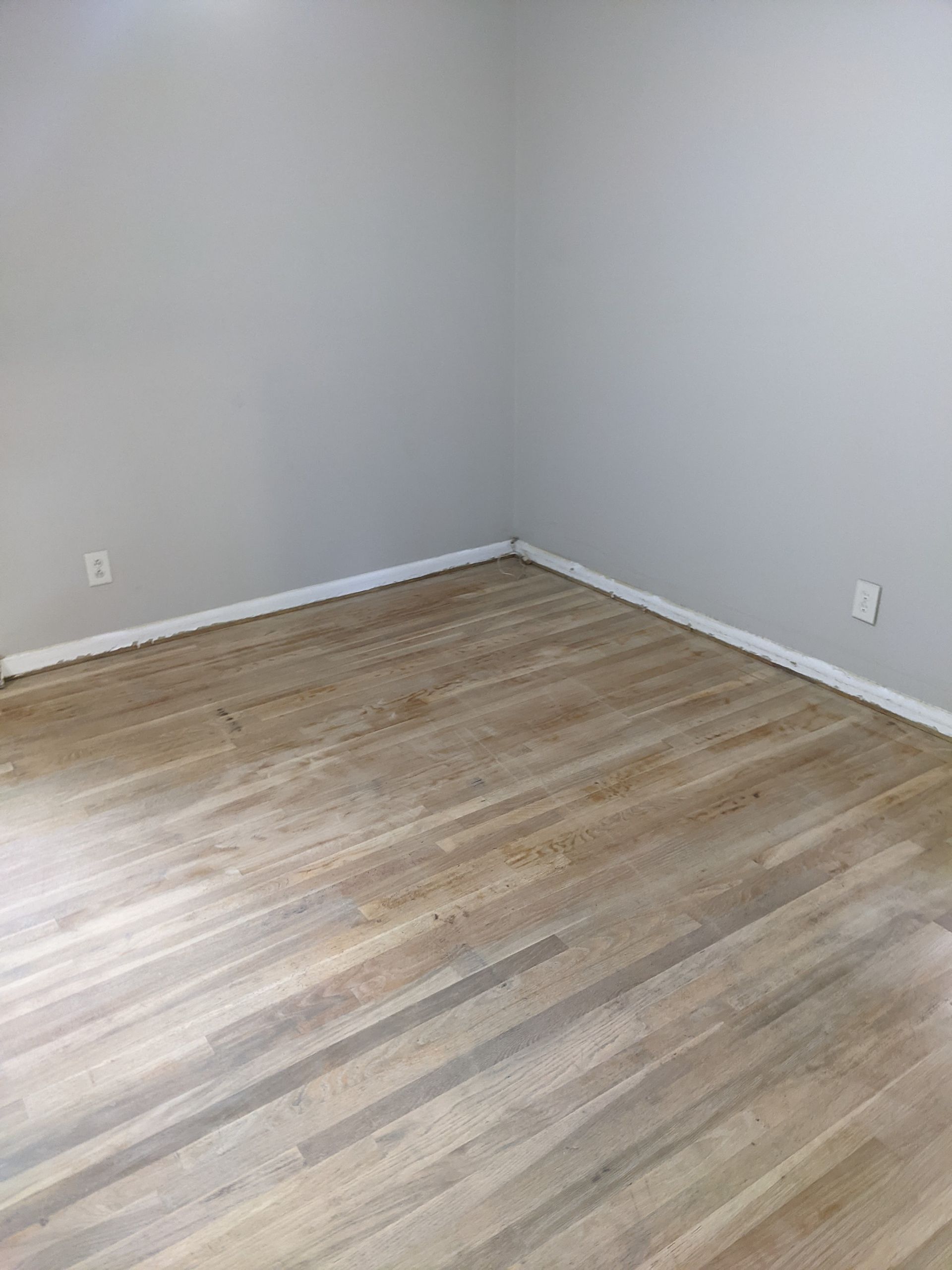 An empty room with hardwood floors and white walls.