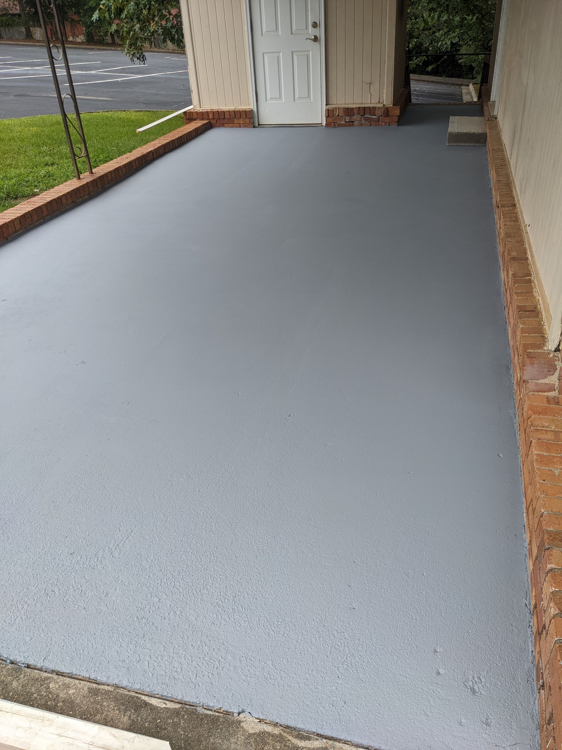 A gray concrete driveway with a white door in the background.