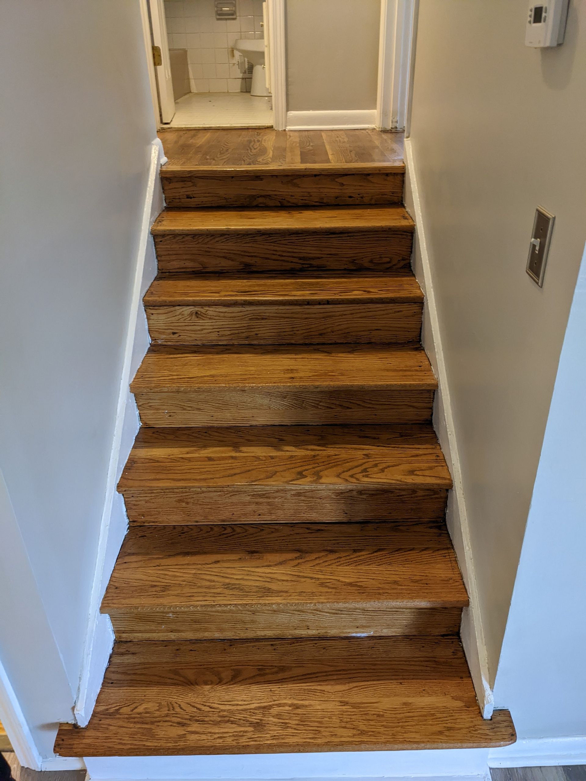 A set of wooden stairs leading up to a bathroom in a house.