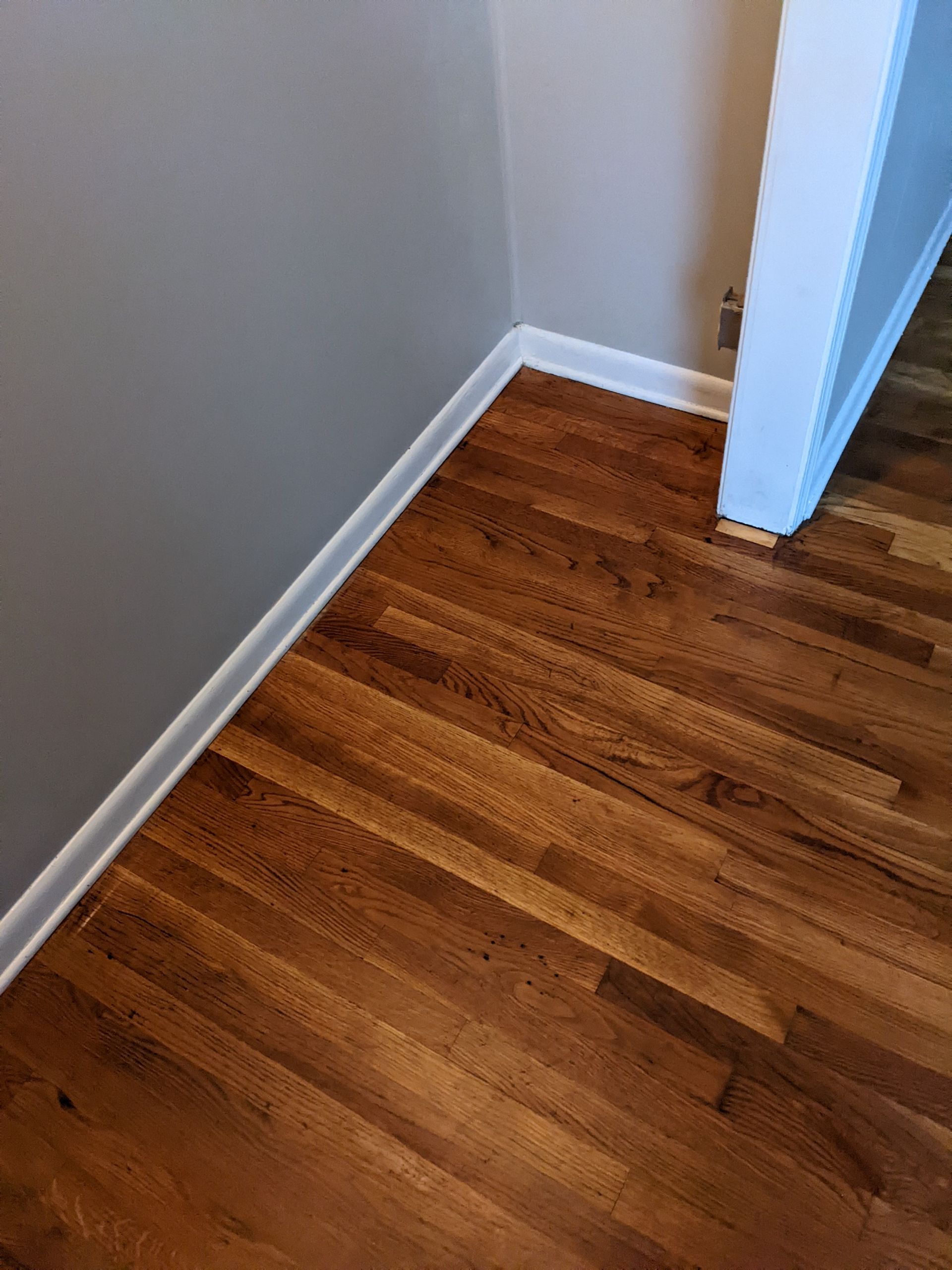 A wooden floor in a room with a white trim.