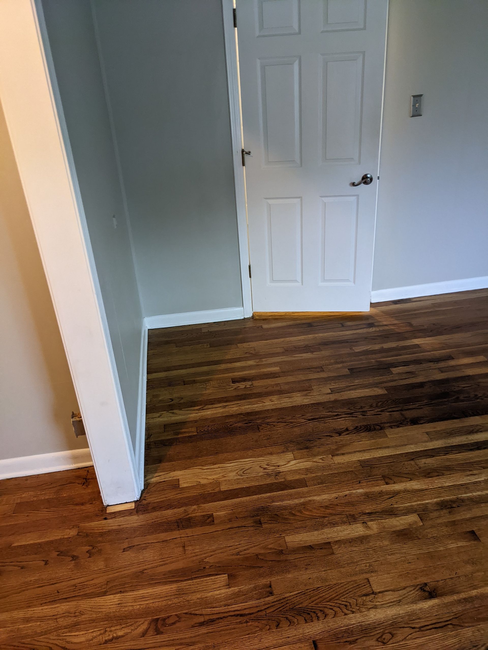 A room with hardwood floors and a white door.
