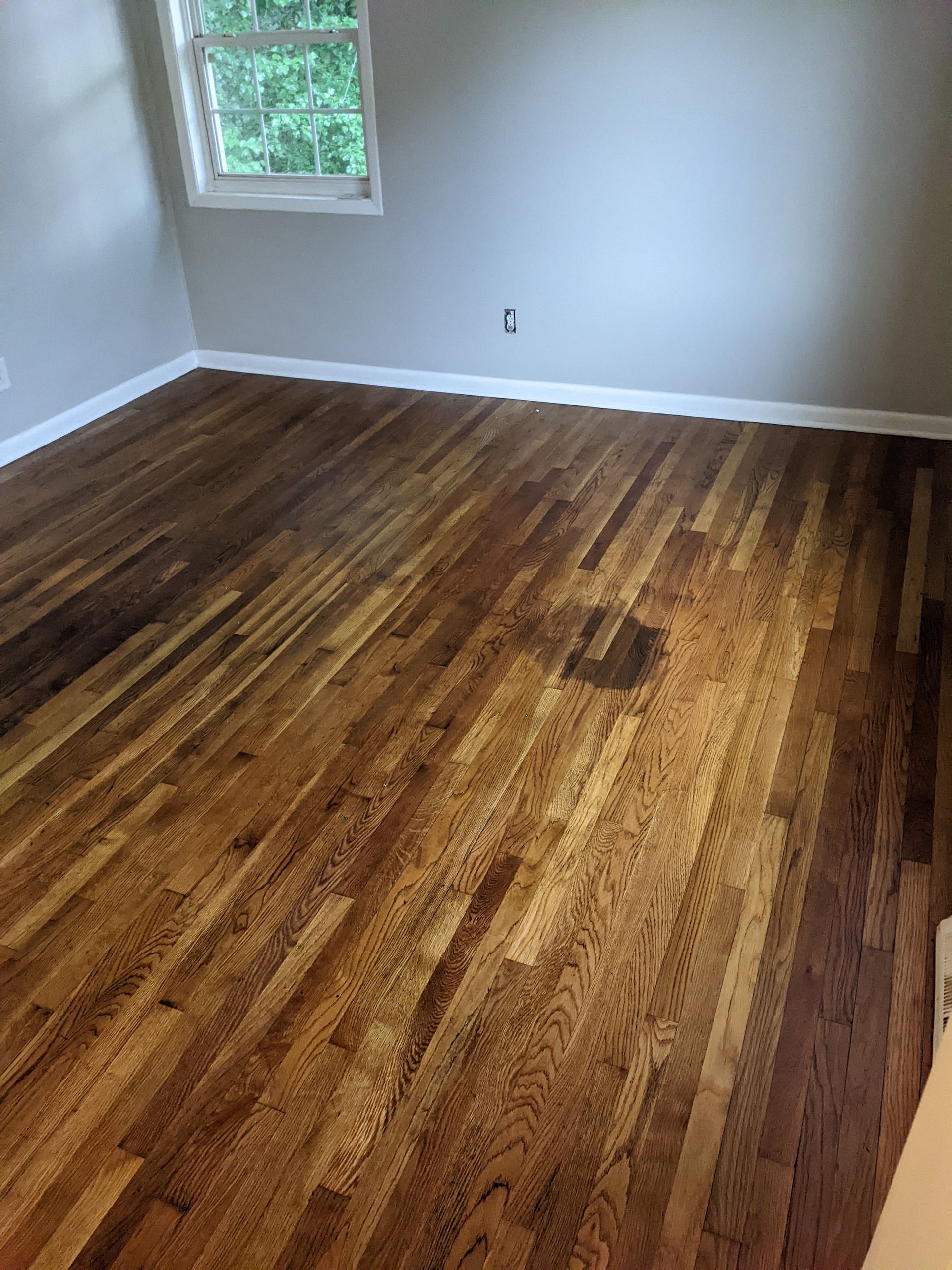 A bedroom with hardwood floors and a window.