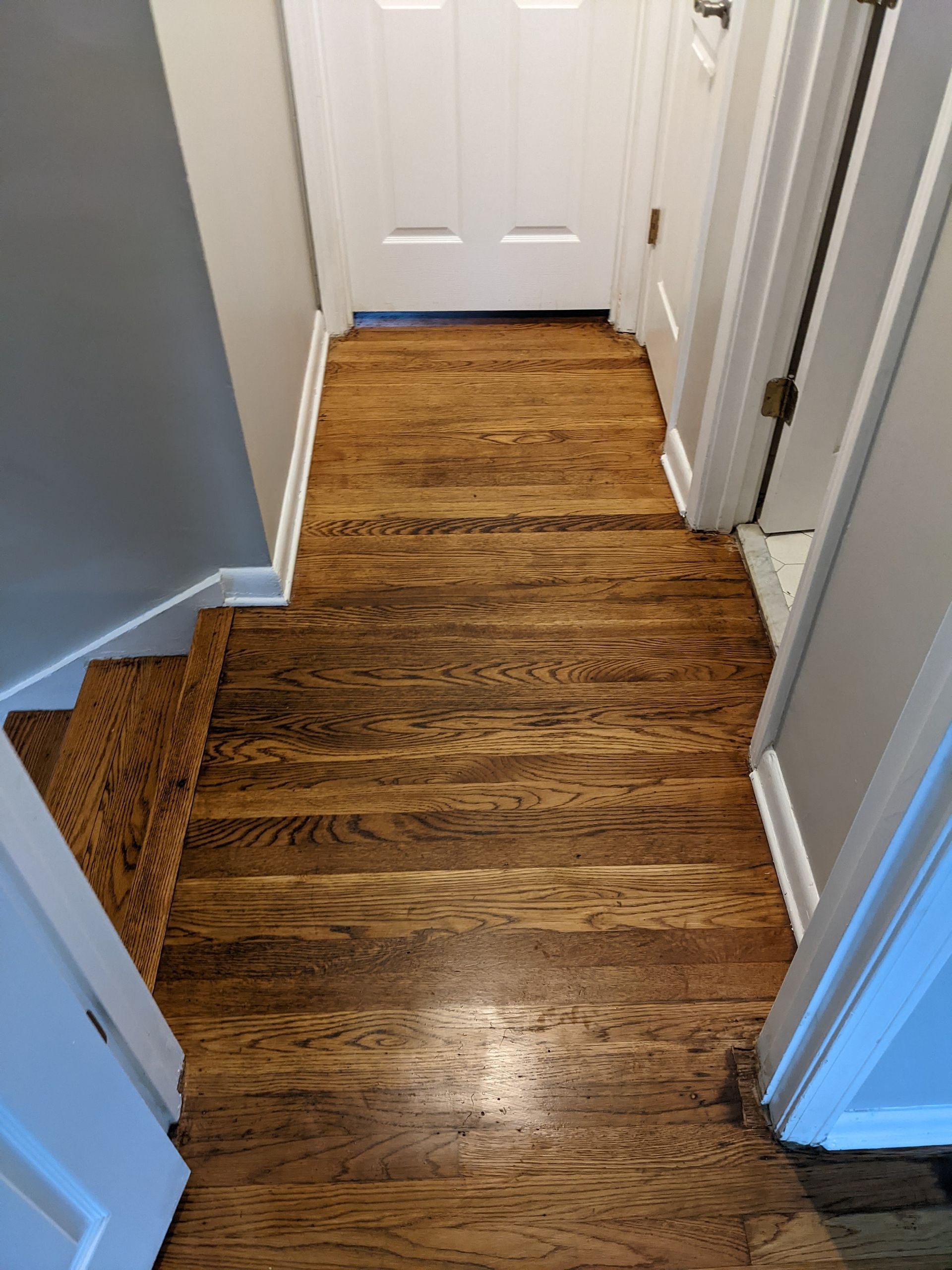A hallway with hardwood floors and stairs in a house.