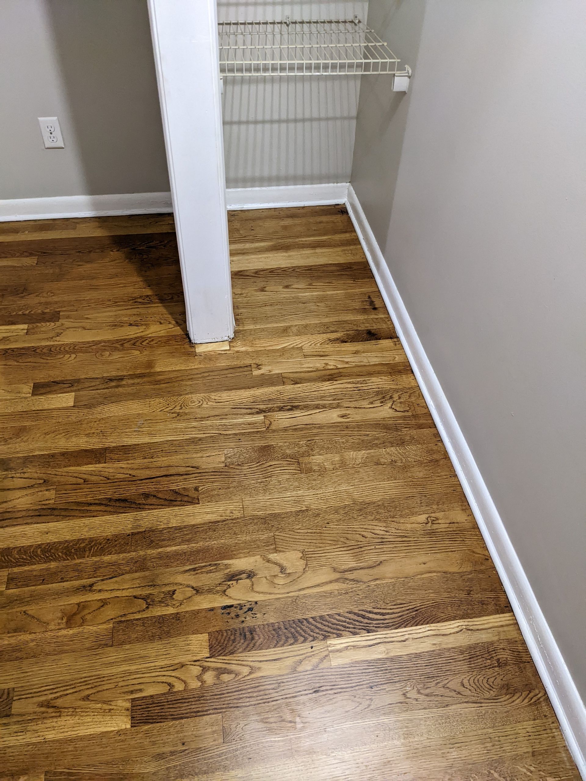 A closet with hardwood floors and a white shelf.