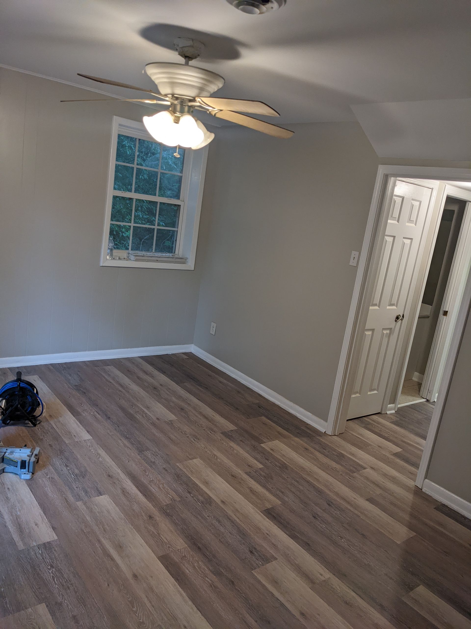 A bedroom with a ceiling fan and a window.