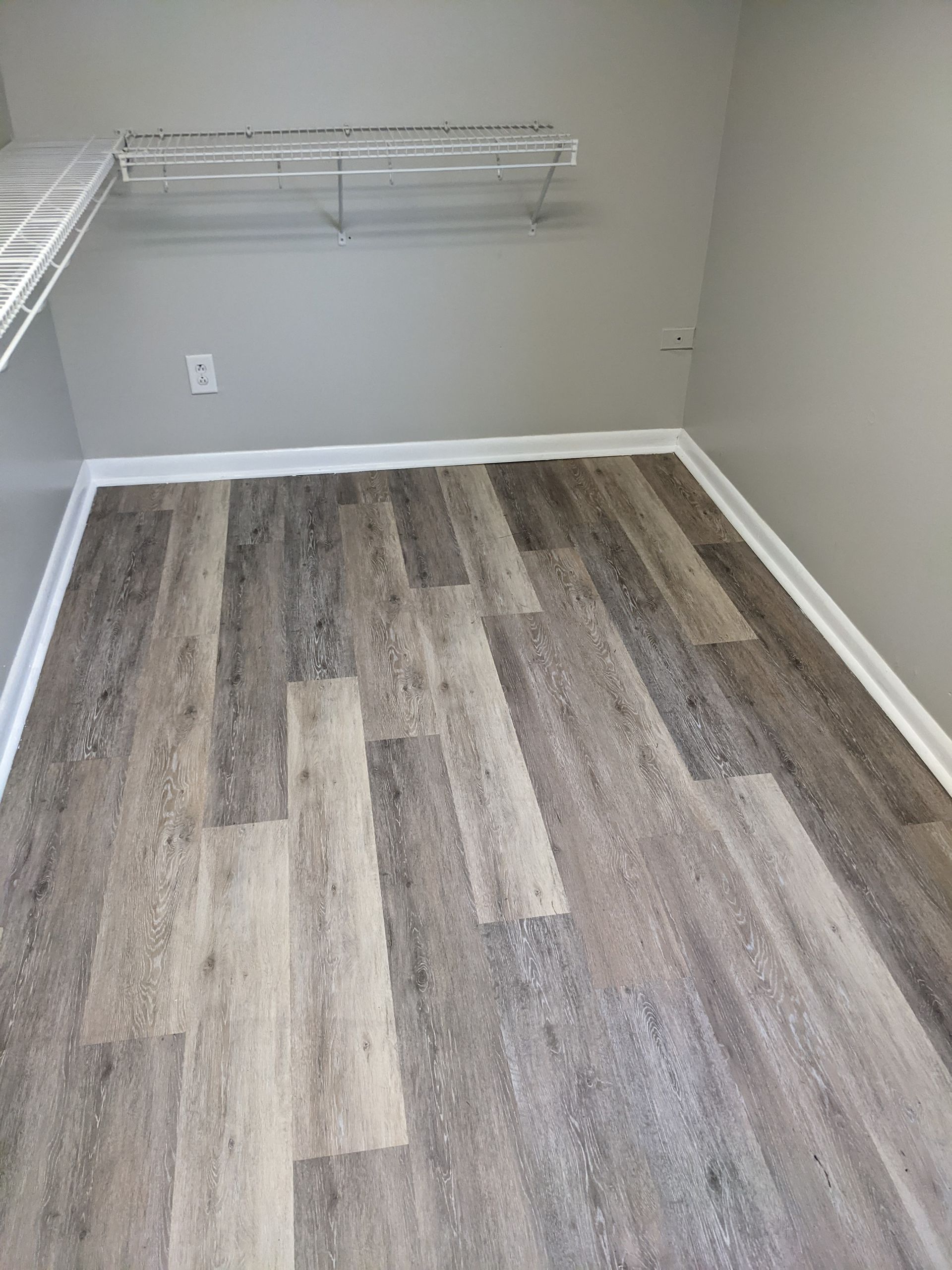 A room with a wooden floor and a shelf on the wall.