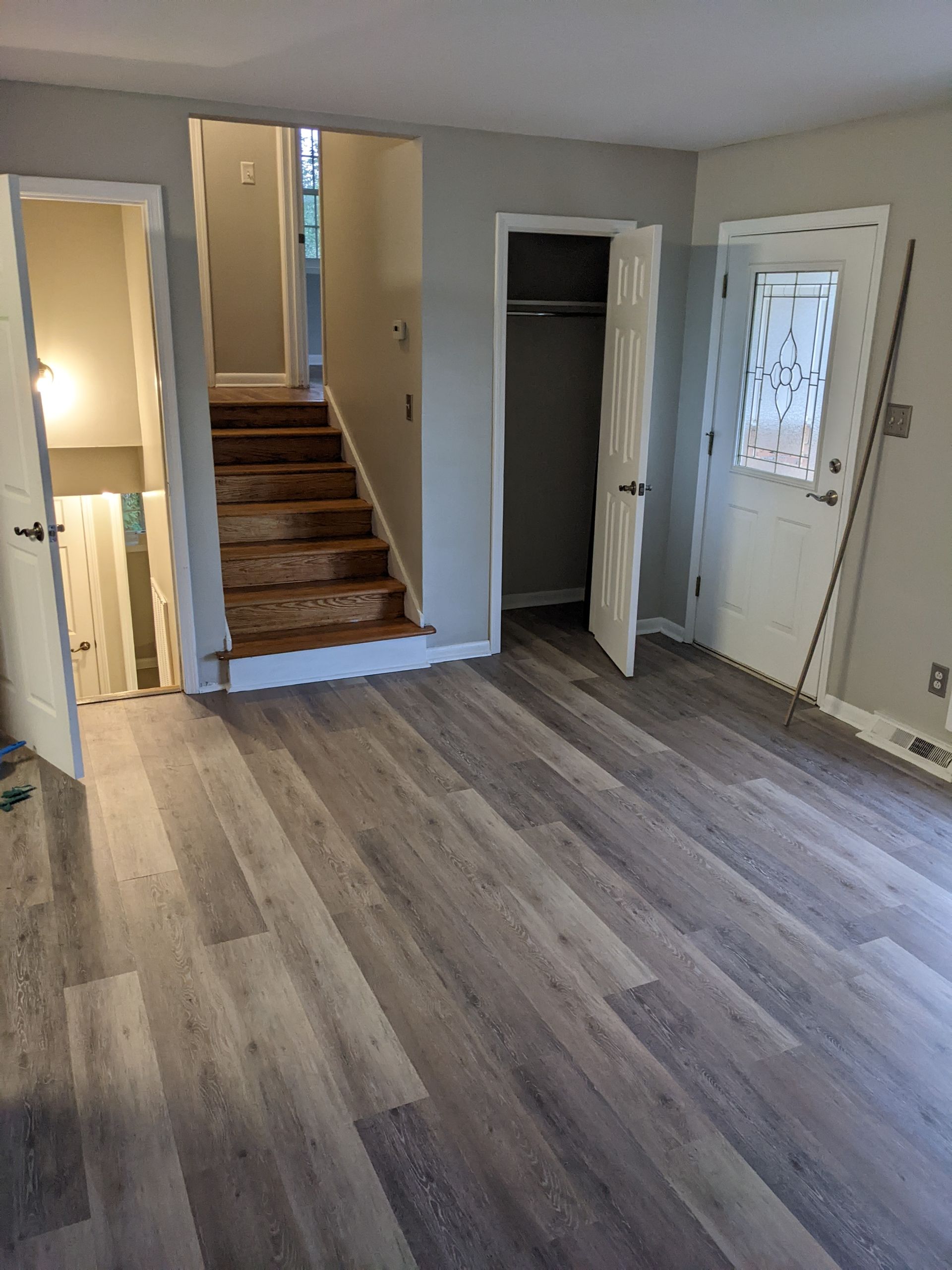 A living room with hardwood floors and stairs leading to the second floor.