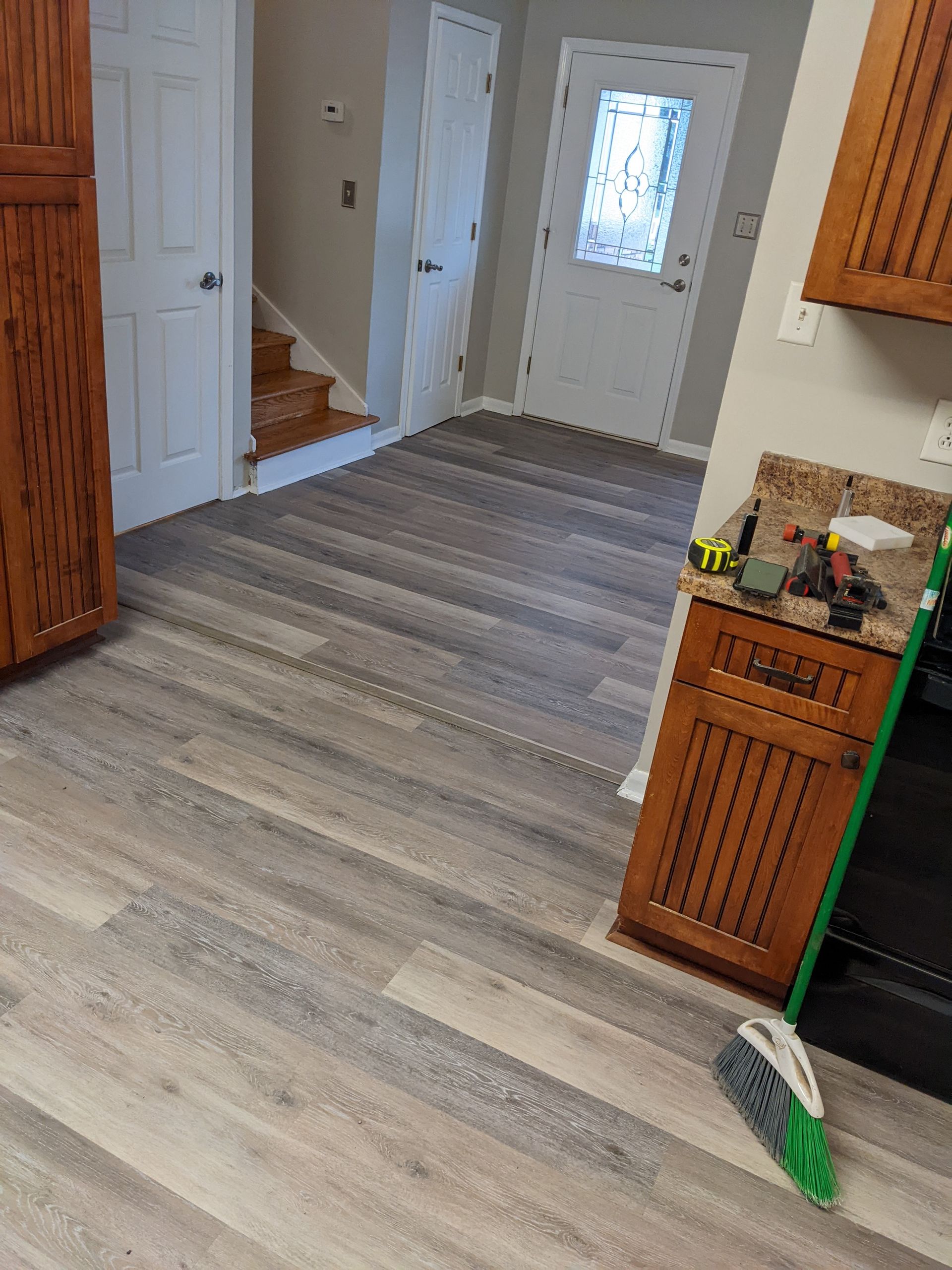 A kitchen with hardwood floors and a broom on the floor.