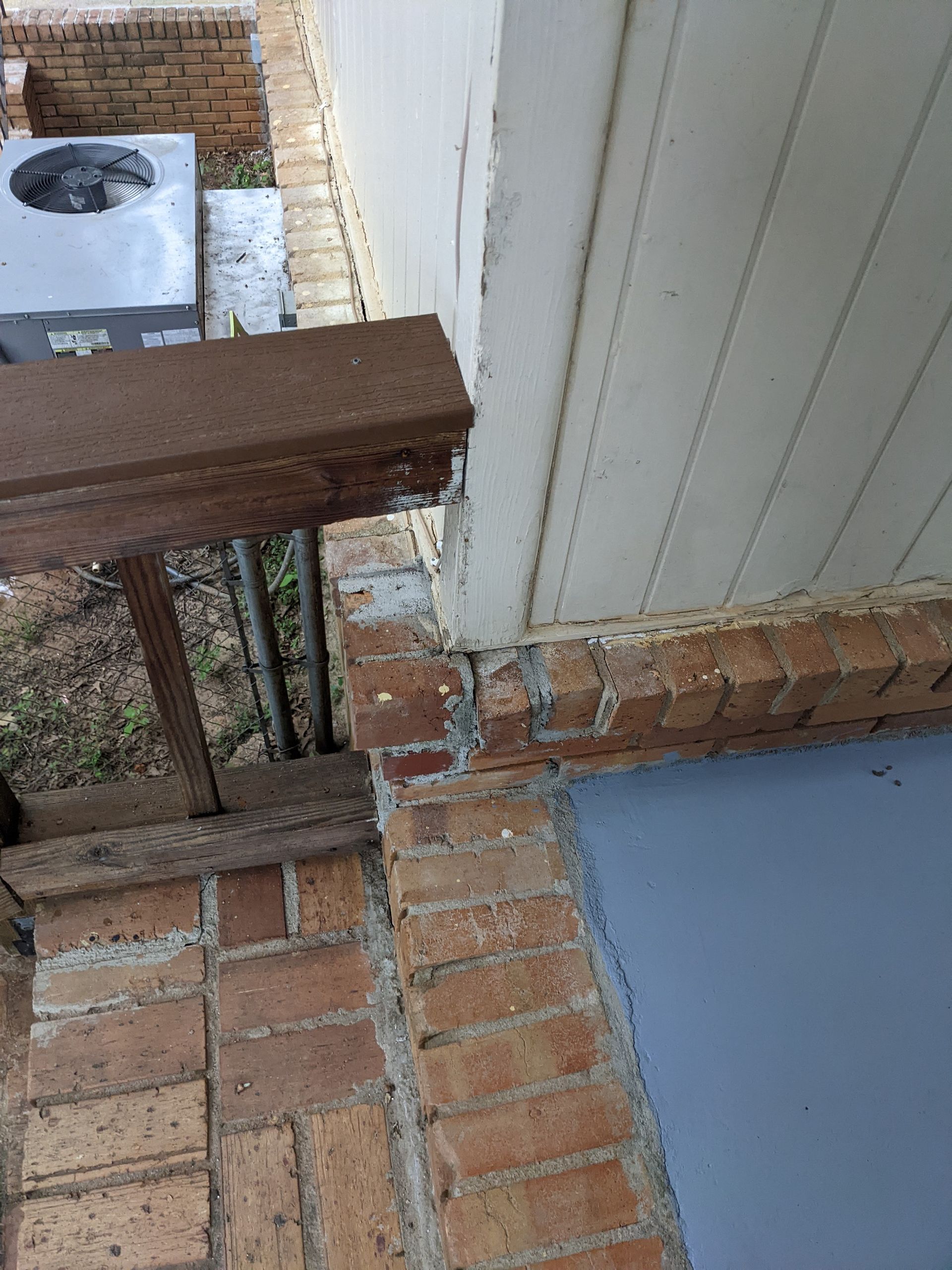 A brick wall with a wooden railing next to it.
