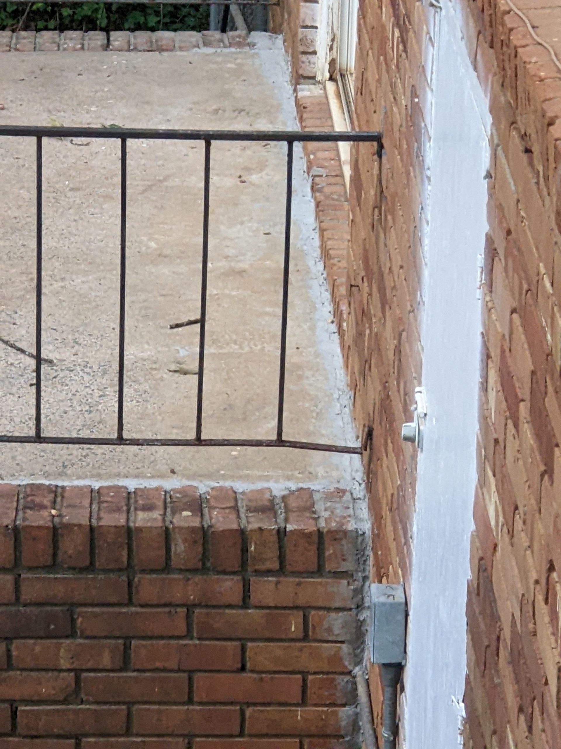 A brick wall with a metal railing on it