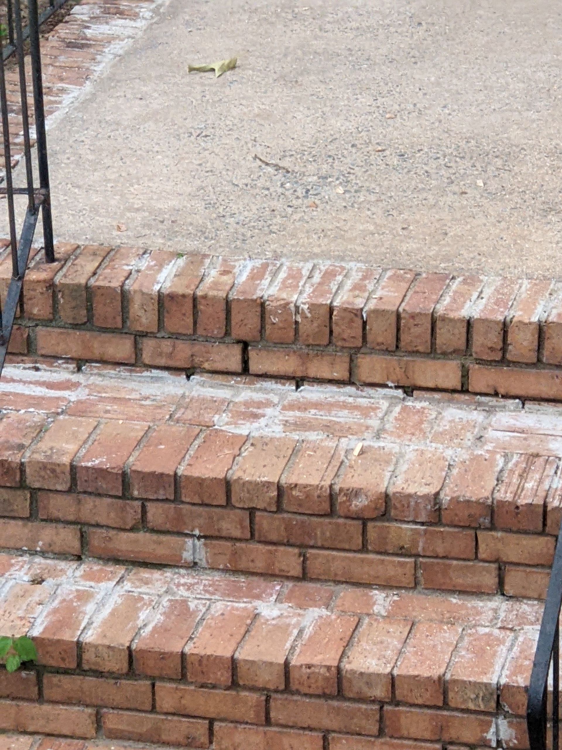 A set of brick stairs with a metal railing