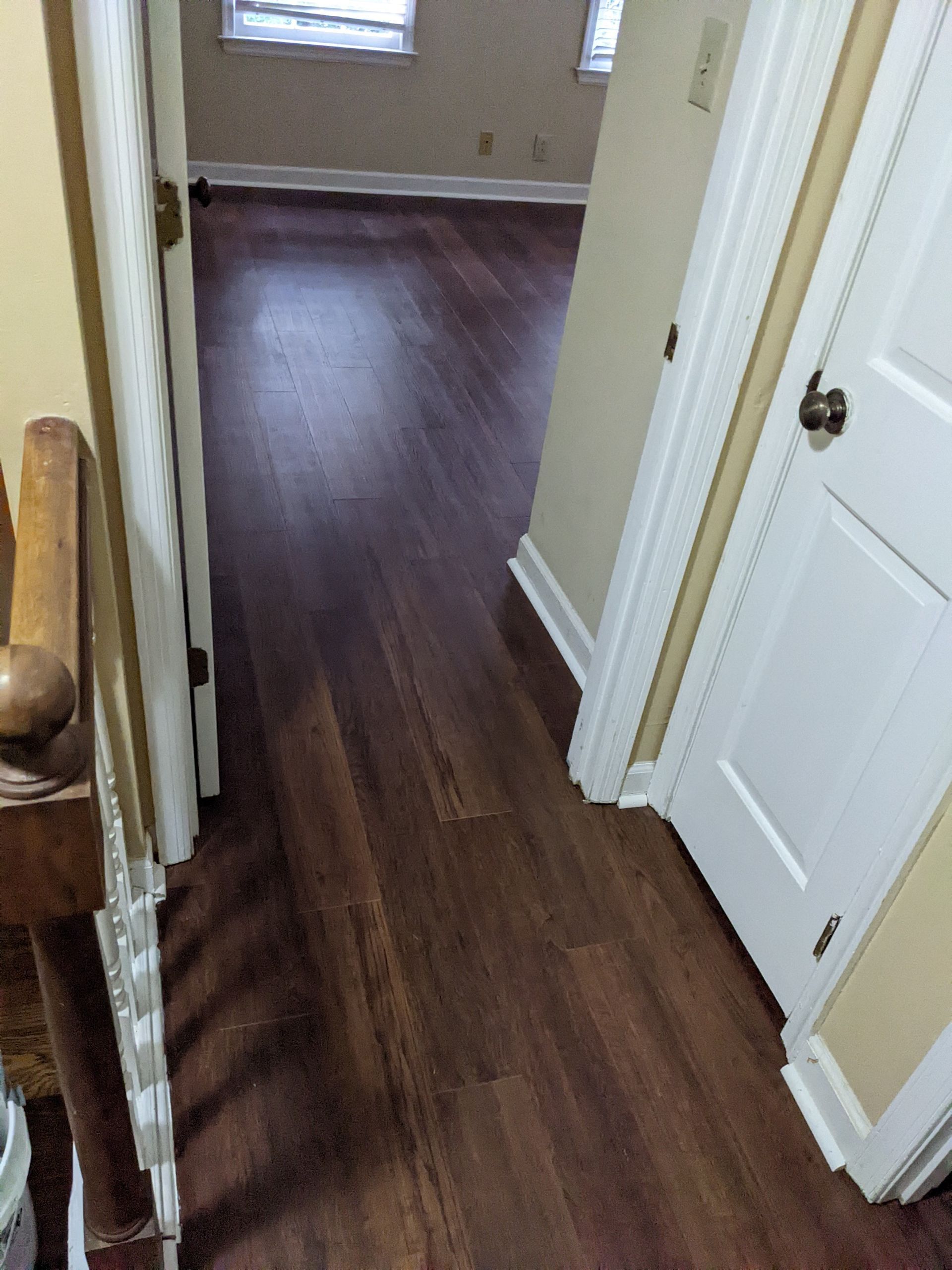 A hallway with hardwood floors and white doors in a house.