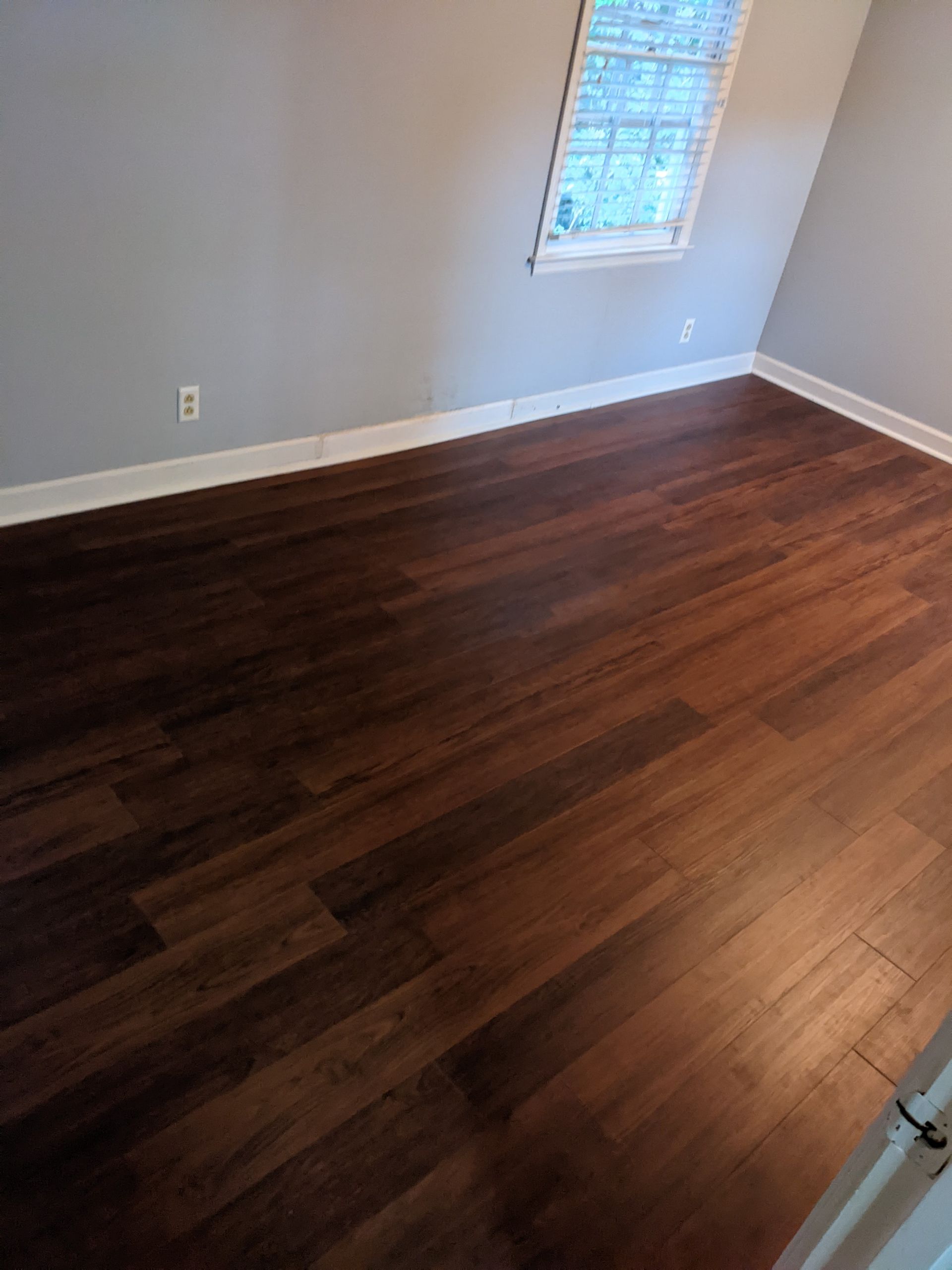 A bedroom with hardwood floors and a window.