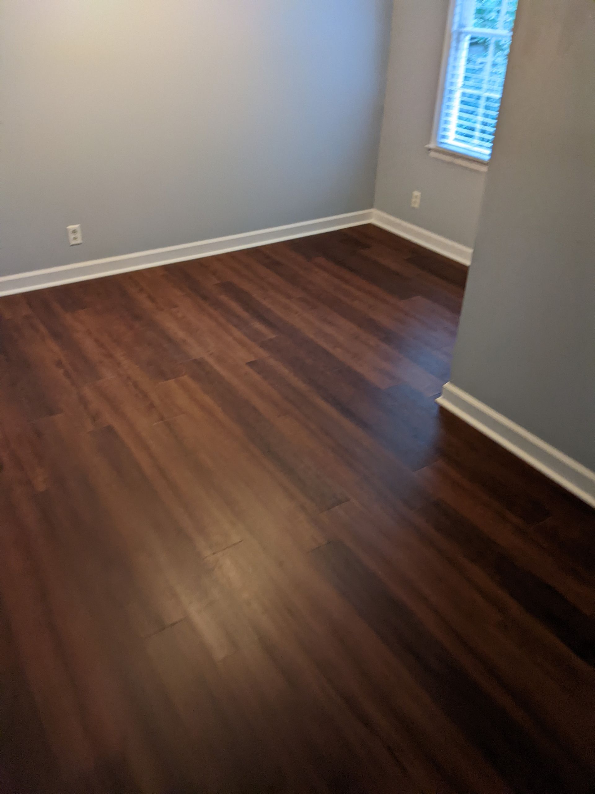A bedroom with hardwood floors and a window.