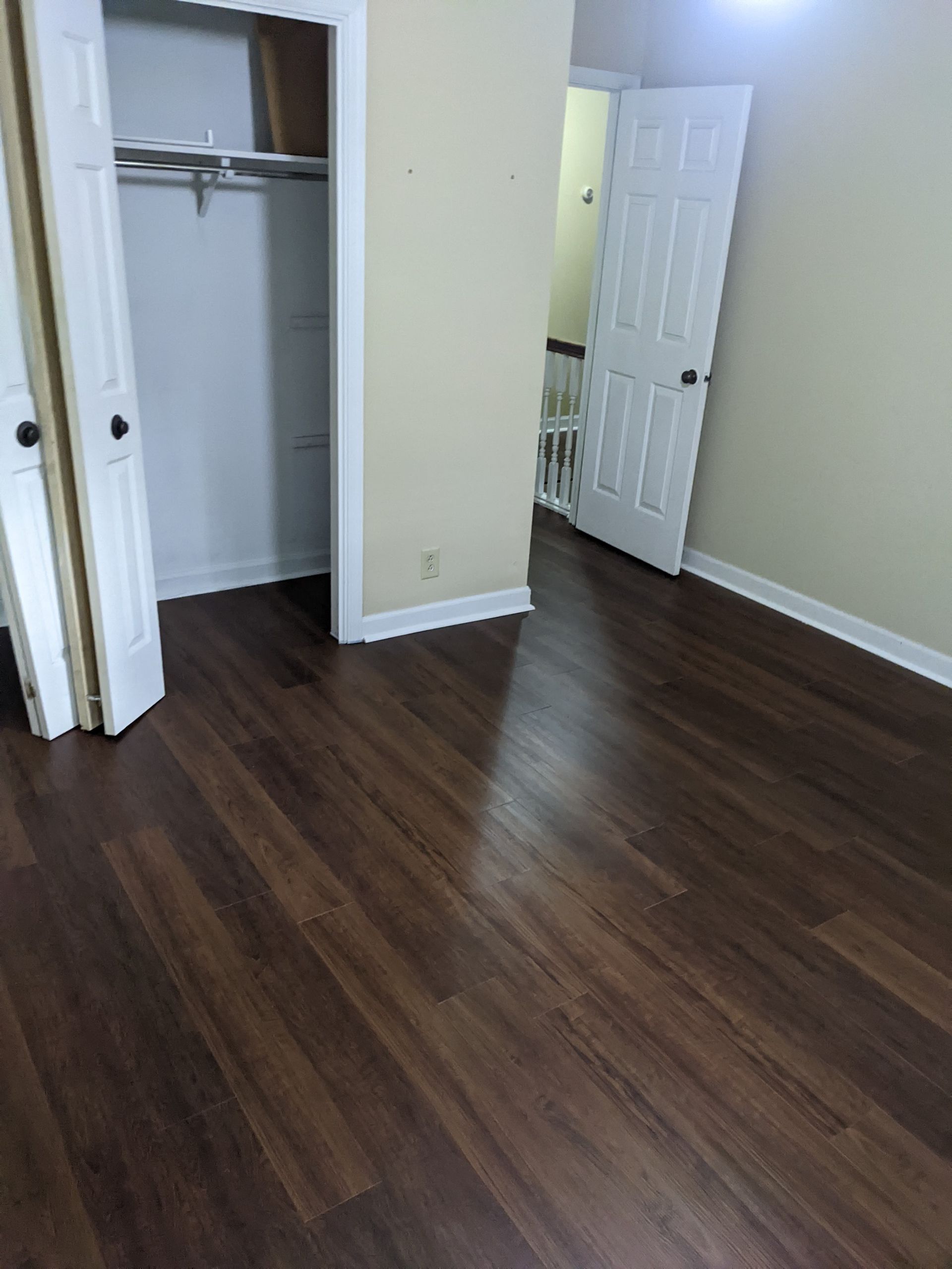 A bedroom with hardwood floors and a closet.