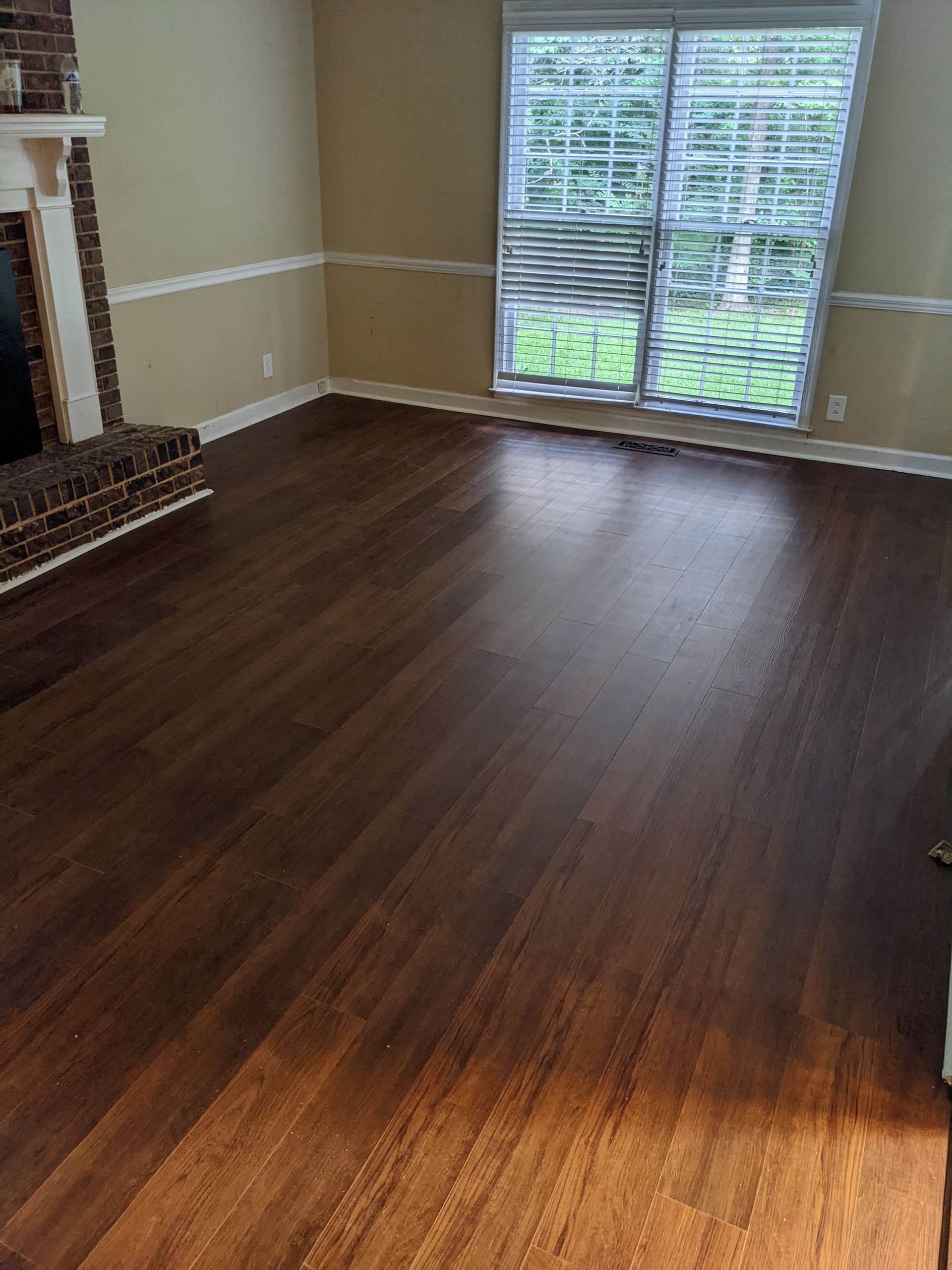 A living room with hardwood floors , a fireplace and sliding glass doors.