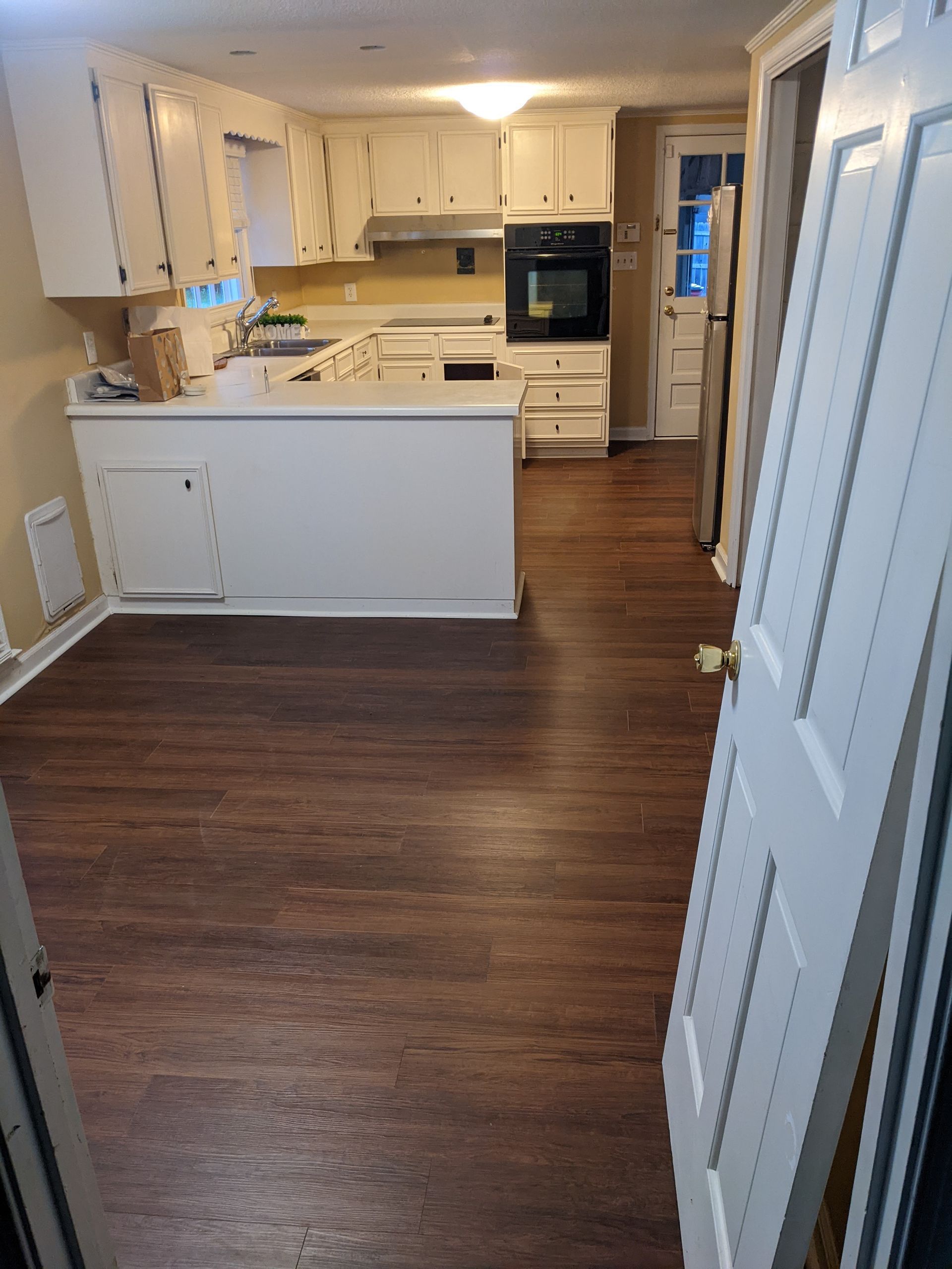 A kitchen with a wooden floor and white cabinets.