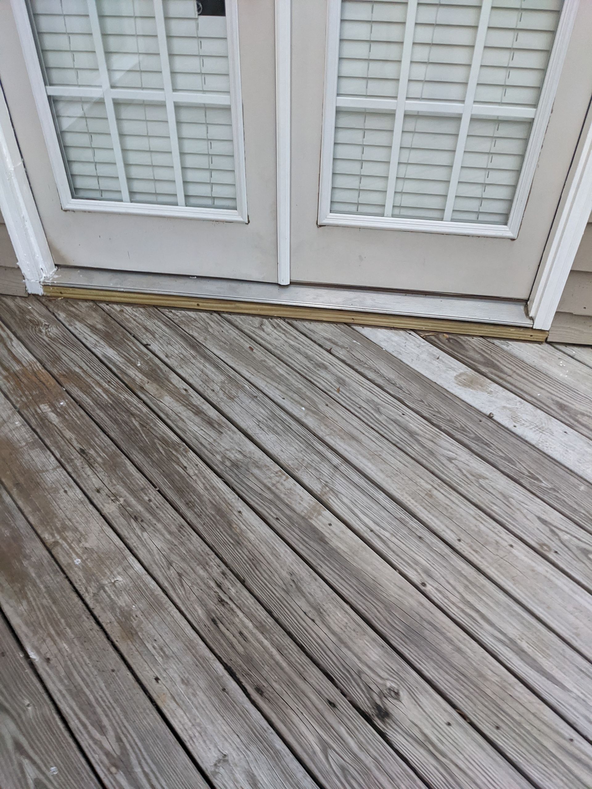 A wooden deck with a sliding glass door in the background.