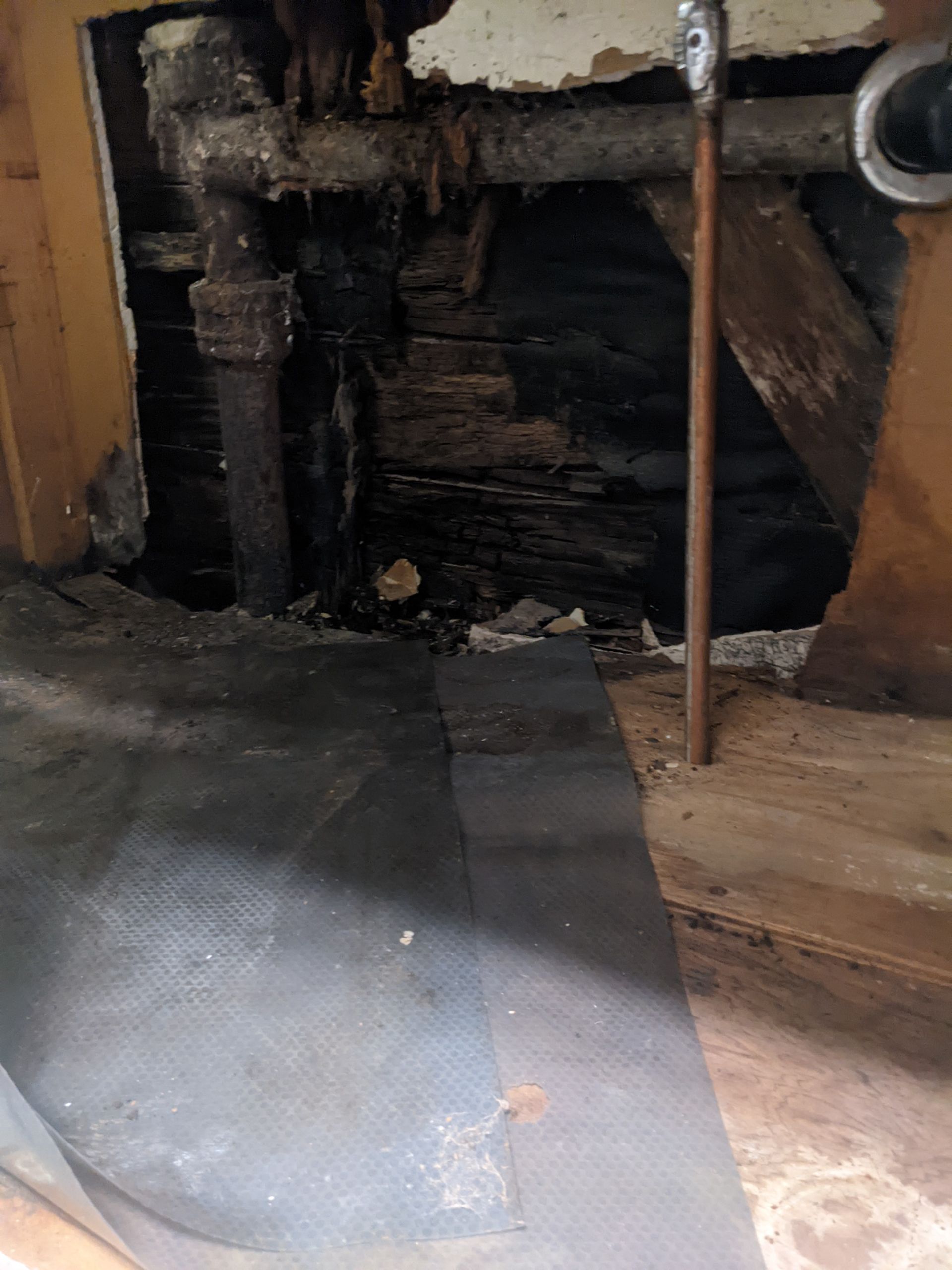 A room with a hole in the wall and a pipe coming out of it.