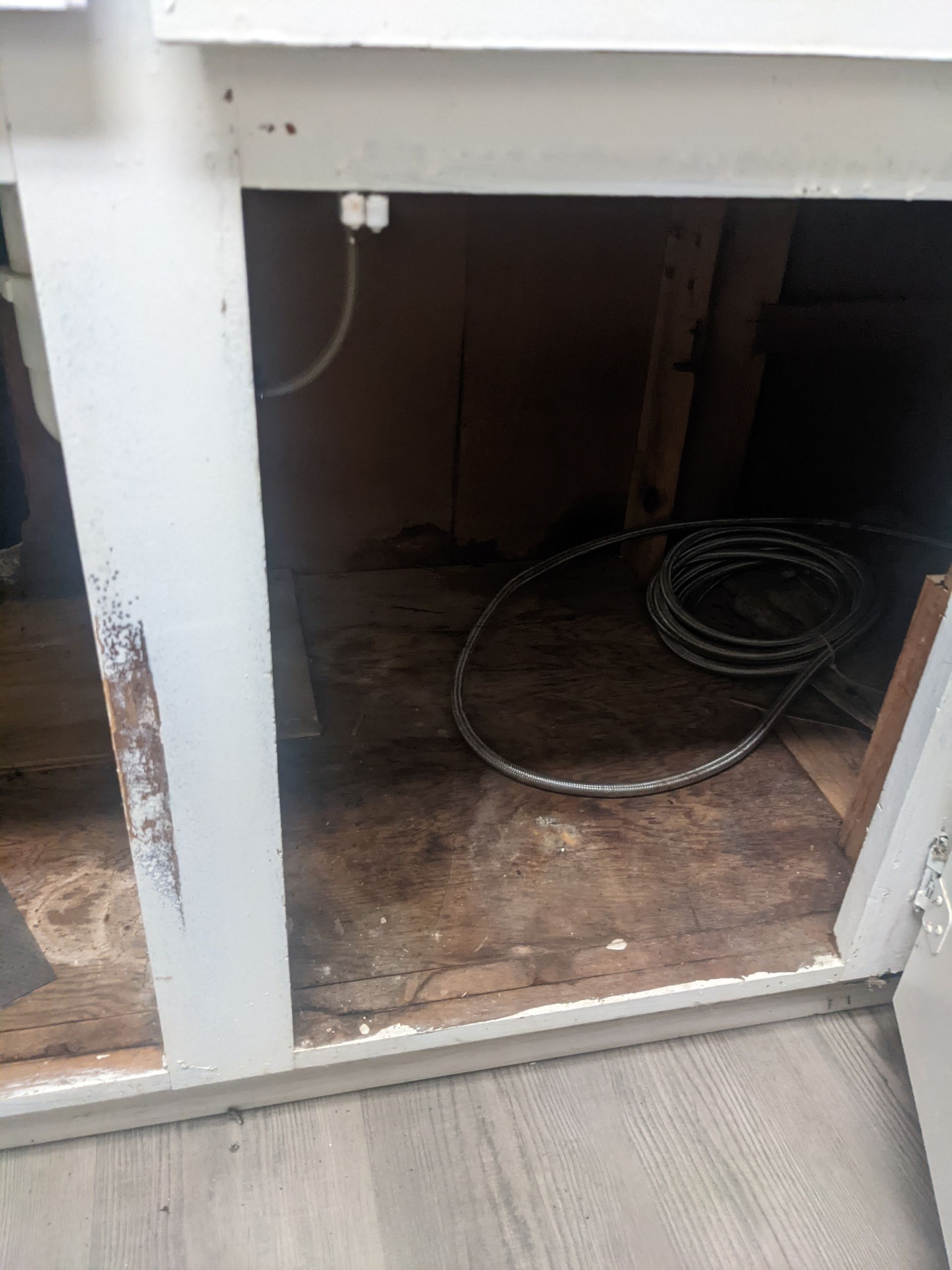 The inside of a cabinet with a hose coming out of it.