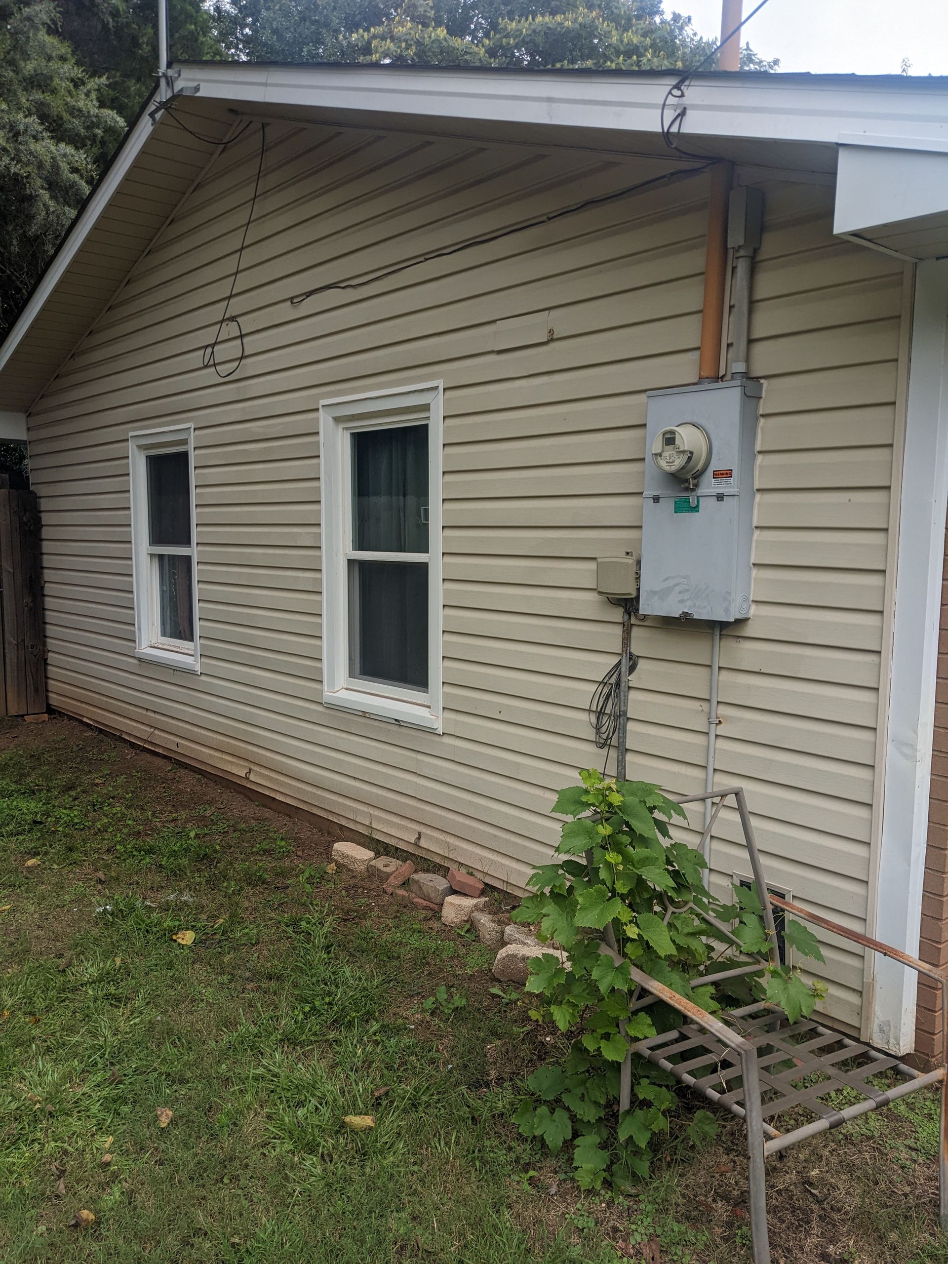 A house with a few windows and a electrical box on the side of it.