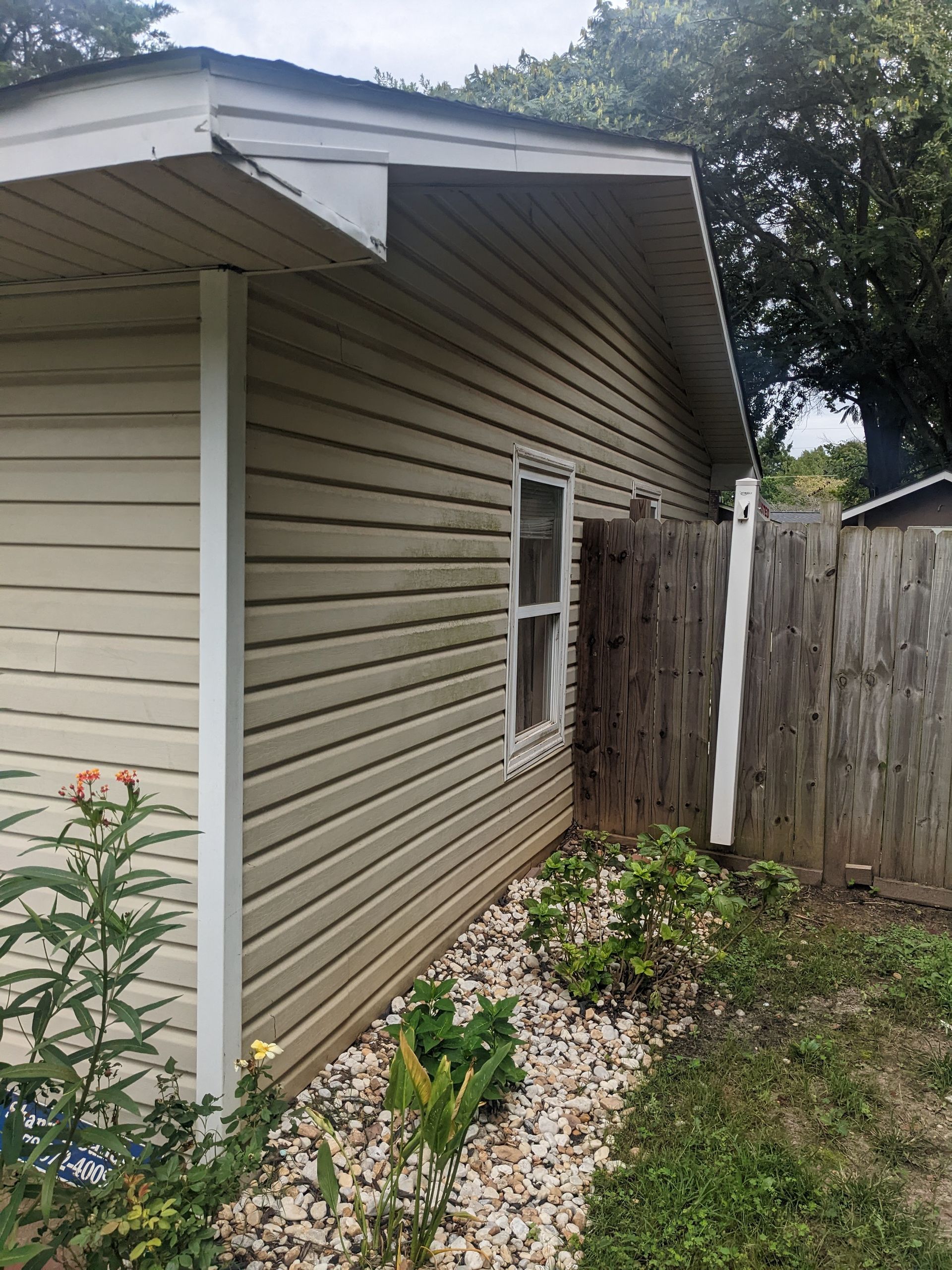The side of a house with a fence and a window.