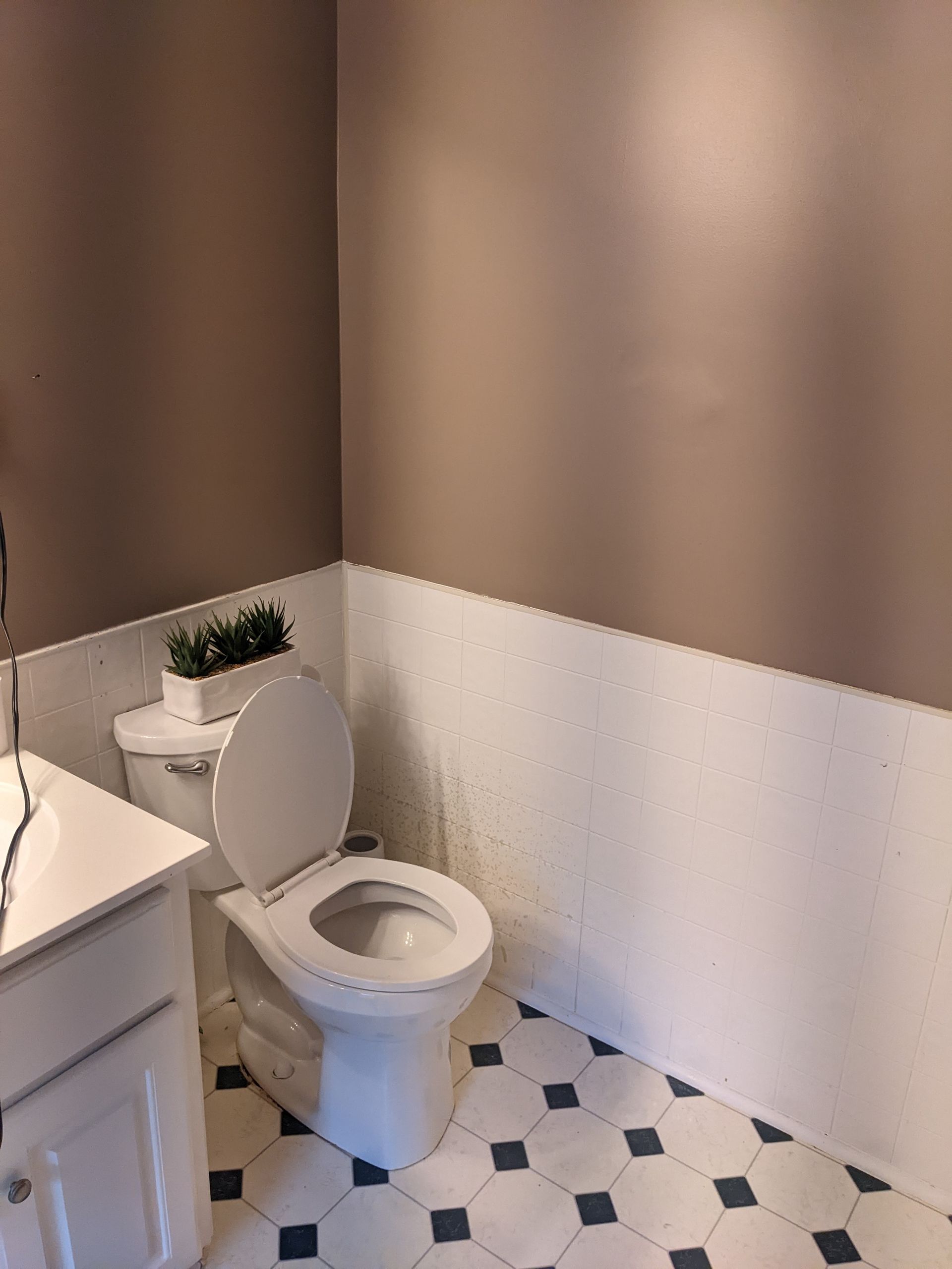 A bathroom with a toilet , sink , and tile floor.